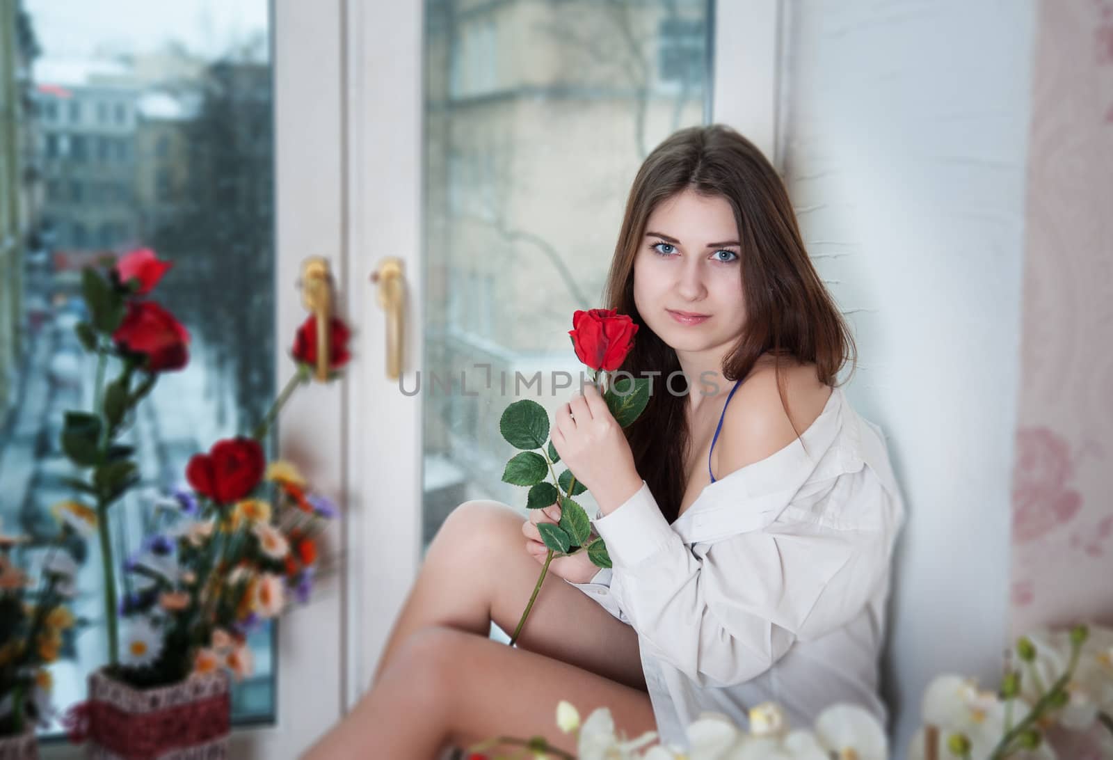 beautiful woman in the flowers on the windowsill