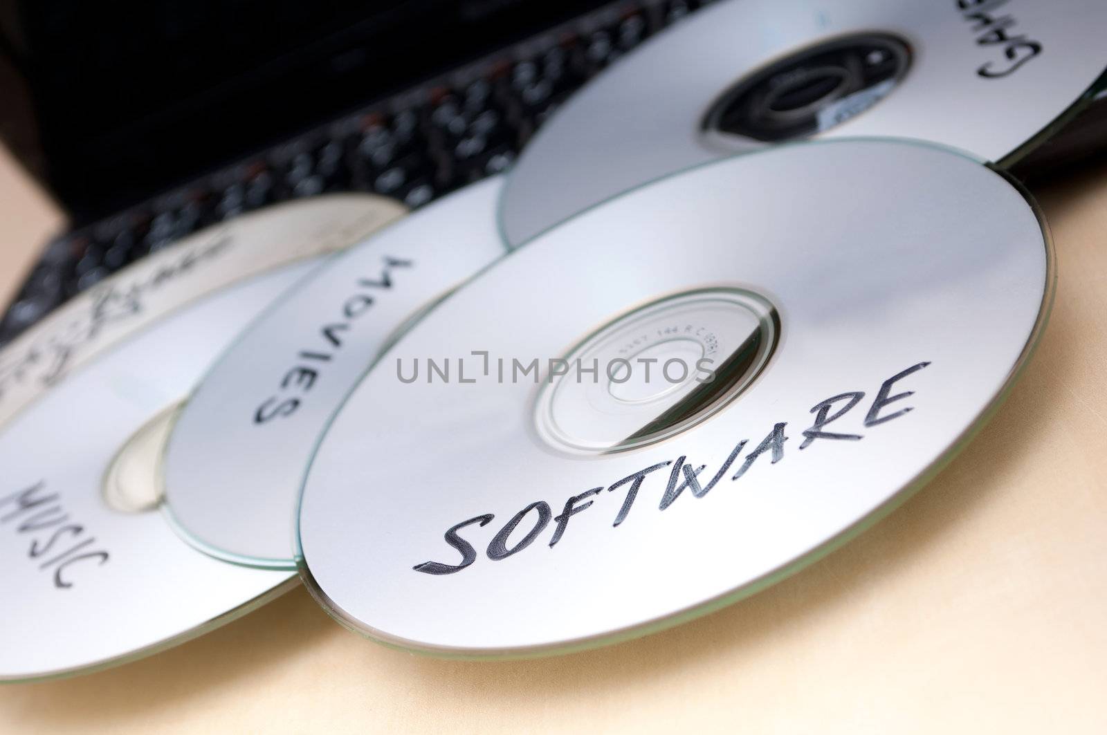 Piracy Concept - Burnt CDs With Illegal Software on Keyboard of Notebook