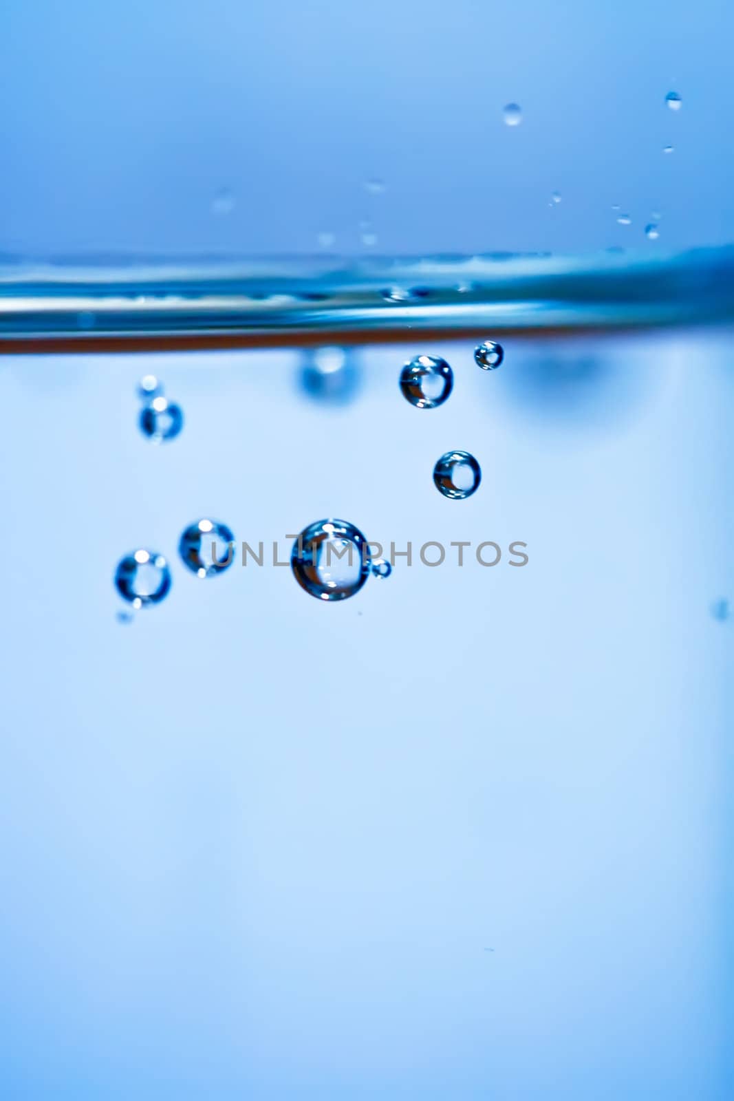 Bubbles in a glass of water on a blue background .