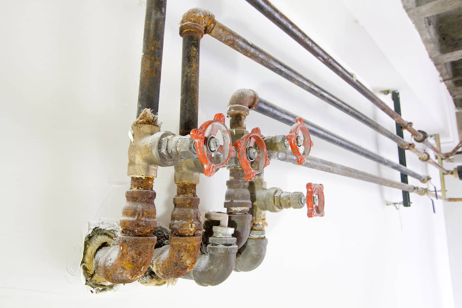 Old Heating Cooling Water Plumbing Pipes with Valves on White Wall