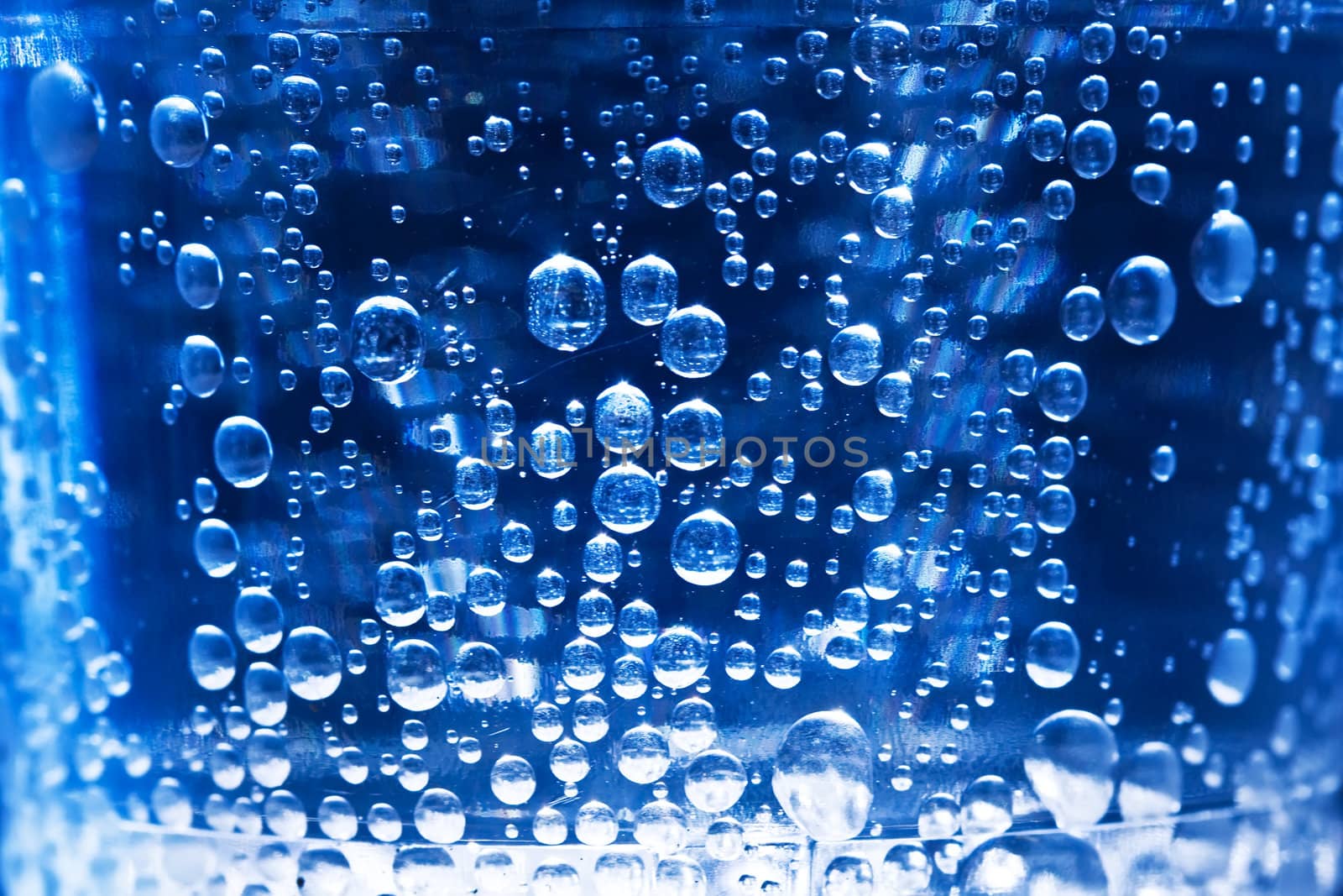 Bubbles in glass of water on a blue background