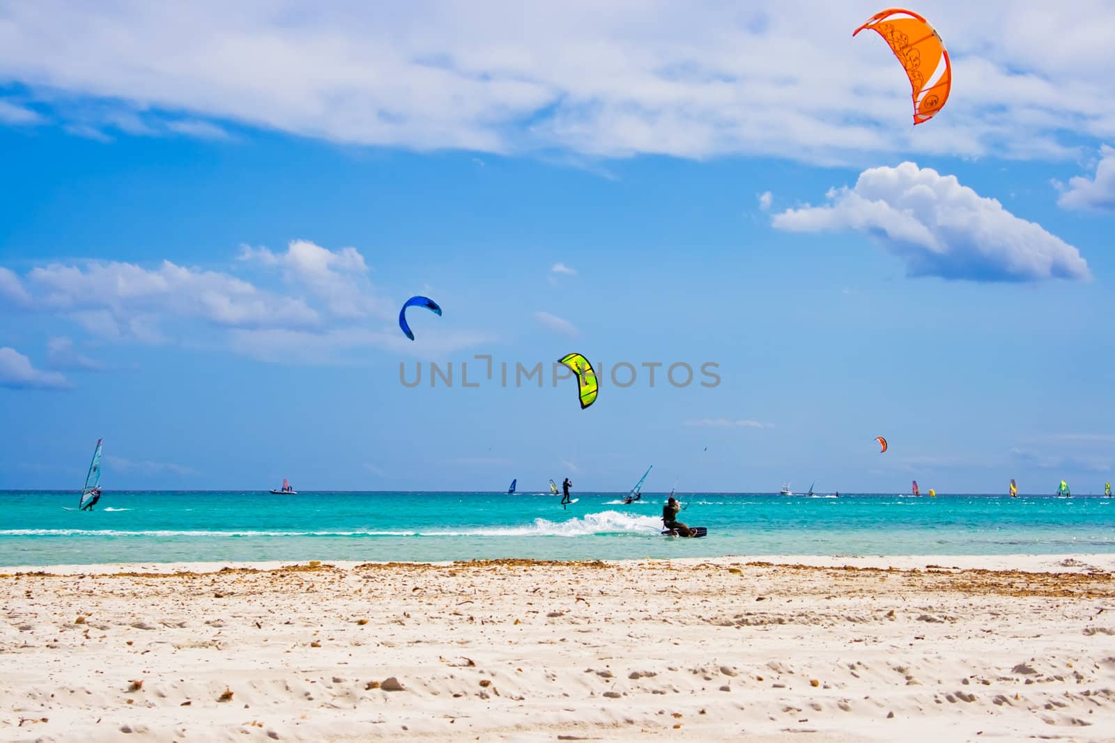 Kitesurfers gliding at high speed around the beach Cinta, Sardinia
