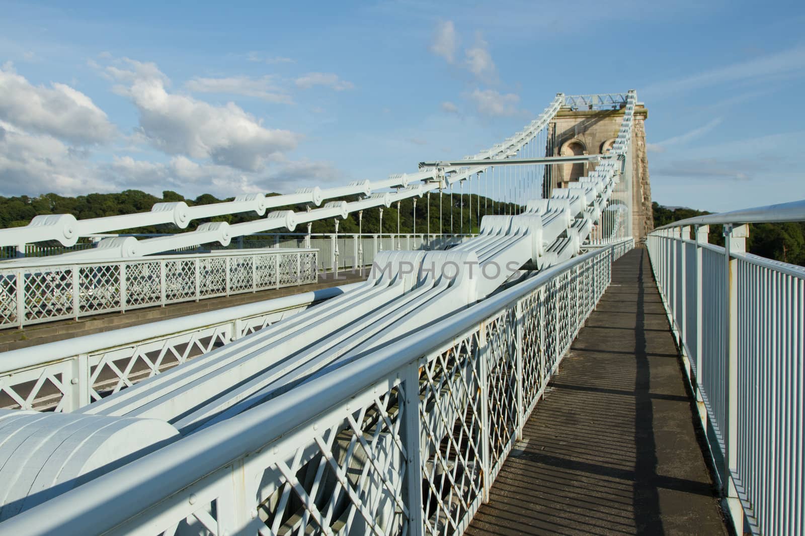 The steel plate chains leading to a supporting tower on the Menai suspension, Gwynedd, Wales, UK, with a walkway against a blue sky.