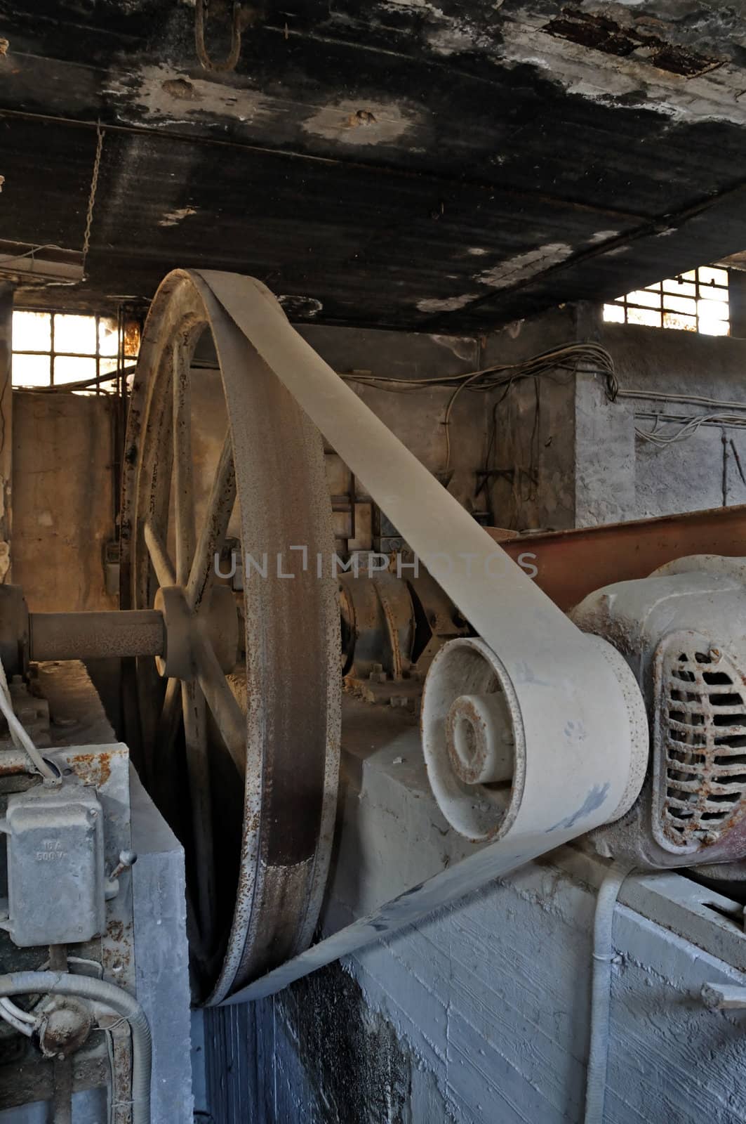 Rusty wheel belt driven machinery in abandoned factory. Industrial interior.