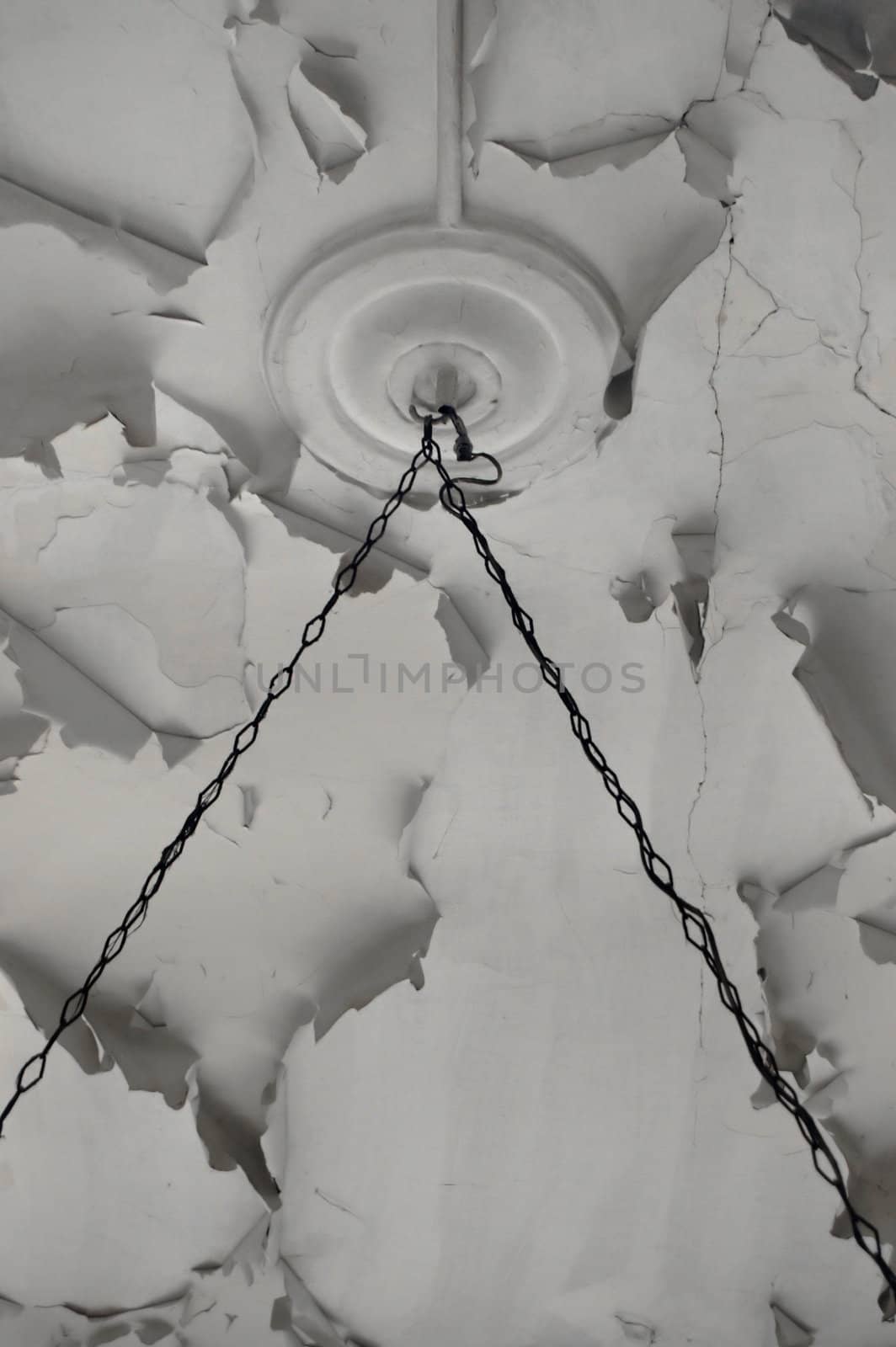 Rusty chains and chipped paint white ceiling texture in abandoned interior.