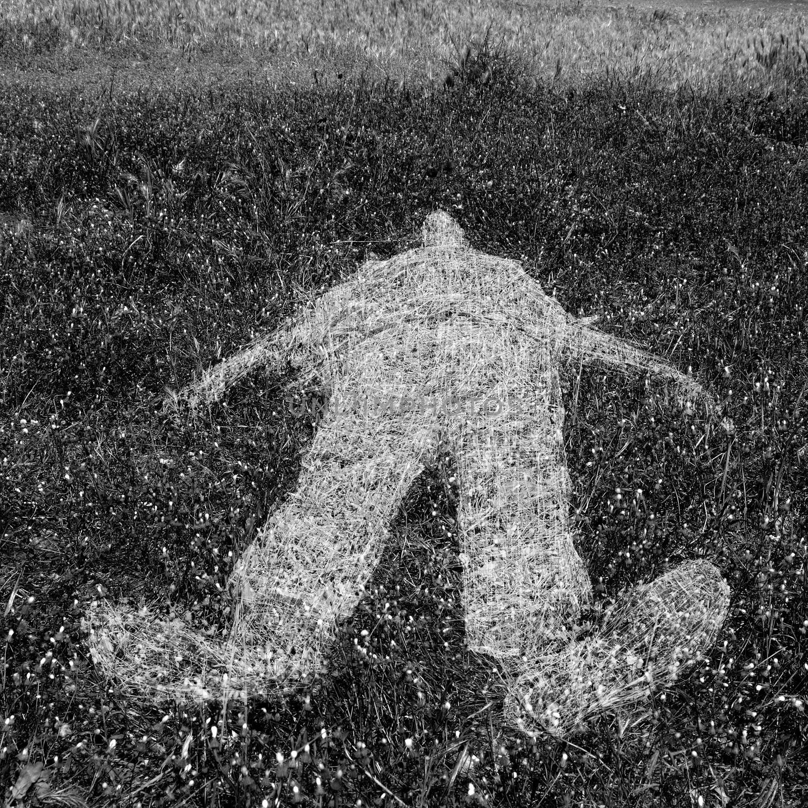 Reclining human figure outline imprinted on grass. Black and white.