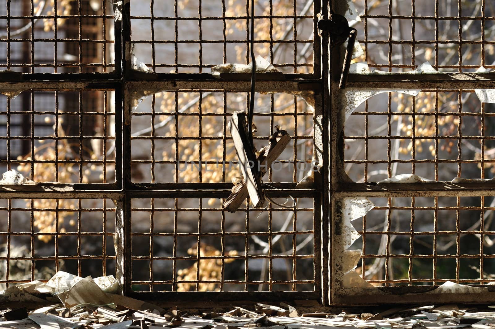Broken glass window and rusty wire mesh background in abandoned warehouse.