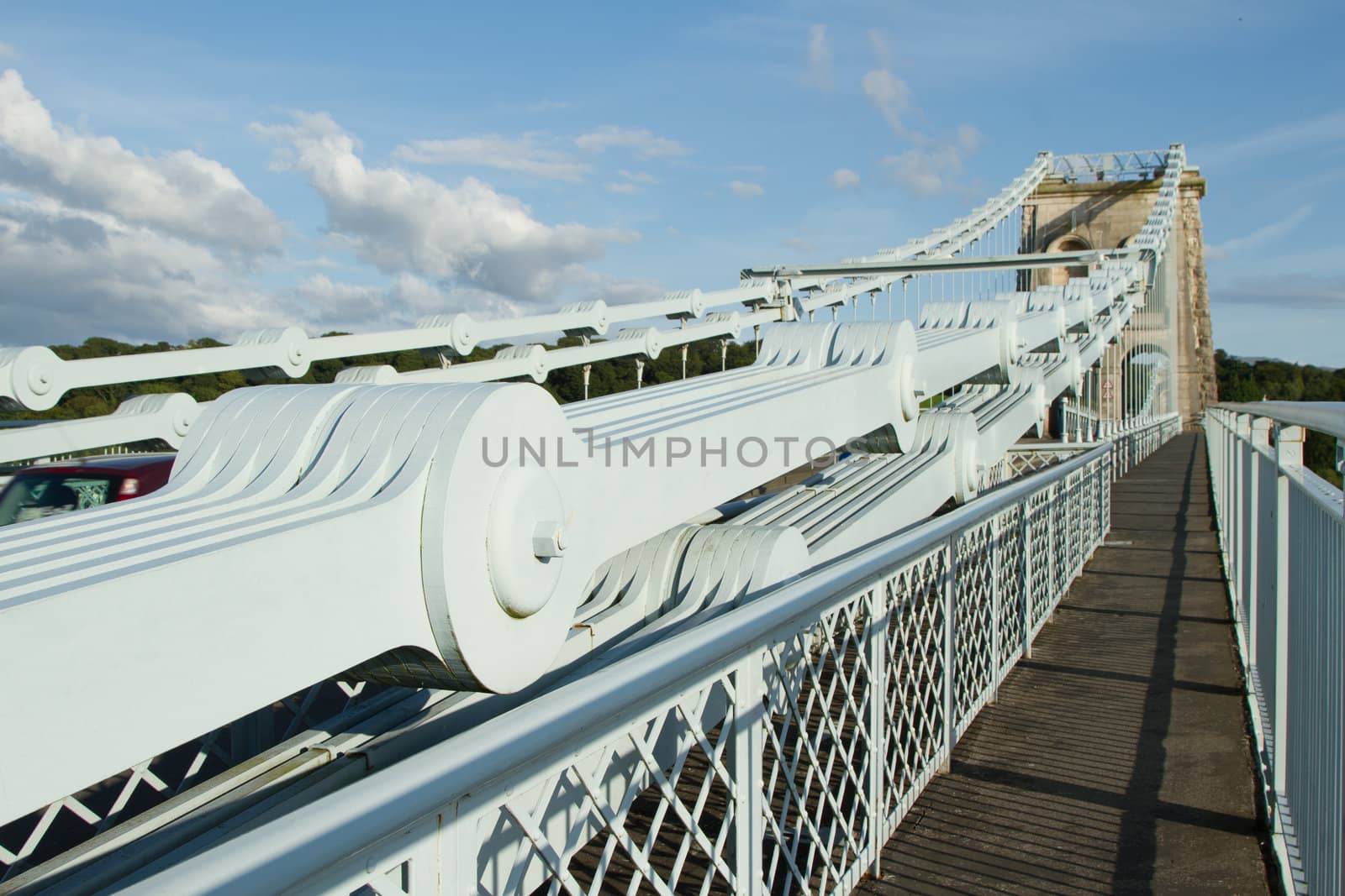 The steel plate chains leading to a supporting tower on the Menai suspension, Gwynedd, Wales, UK, with a walkway against a blue sky.