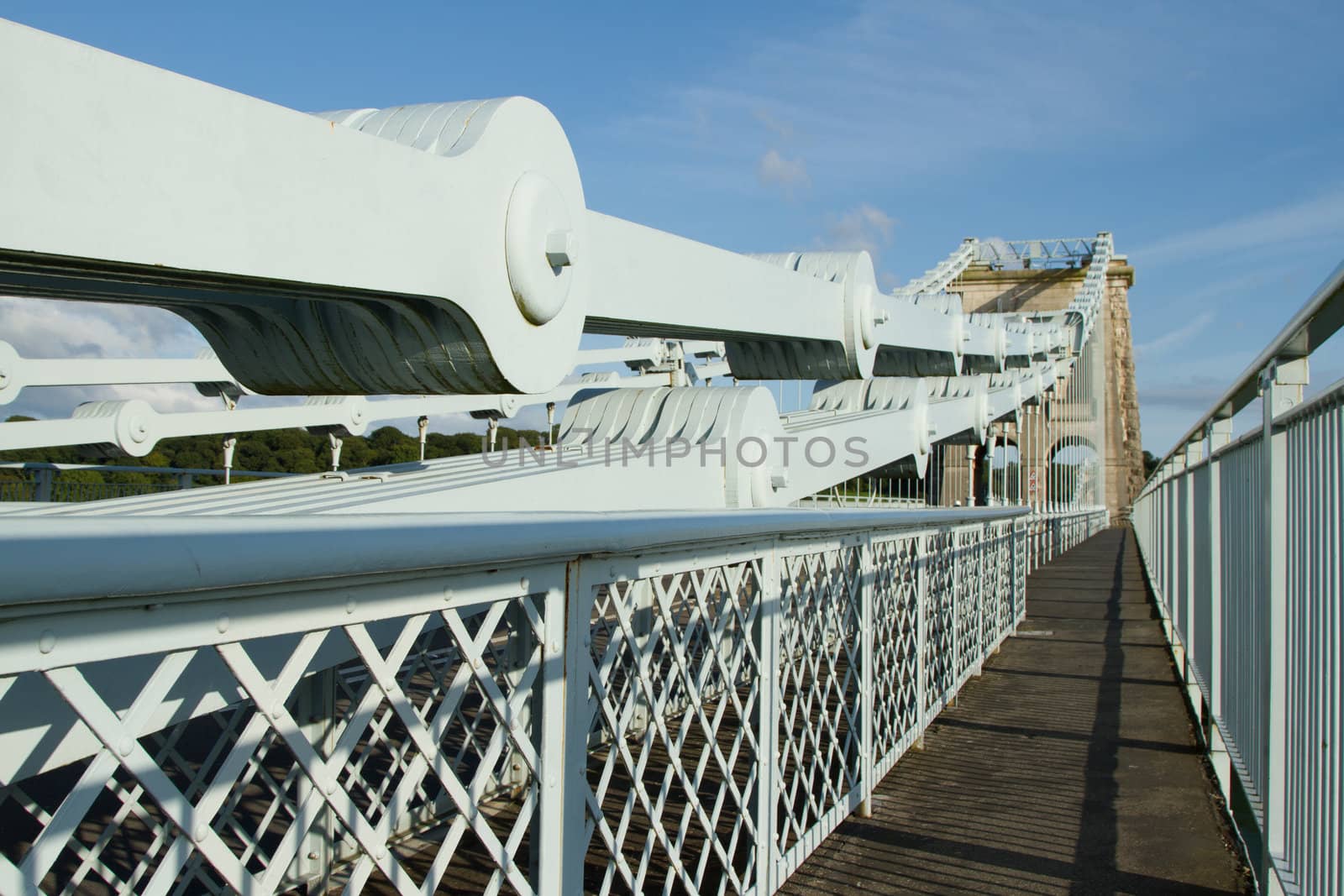 The steel plate chains leading to a supporting tower on the Menai suspension, Gwynedd, Wales, UK, with a walkway against a blue sky.