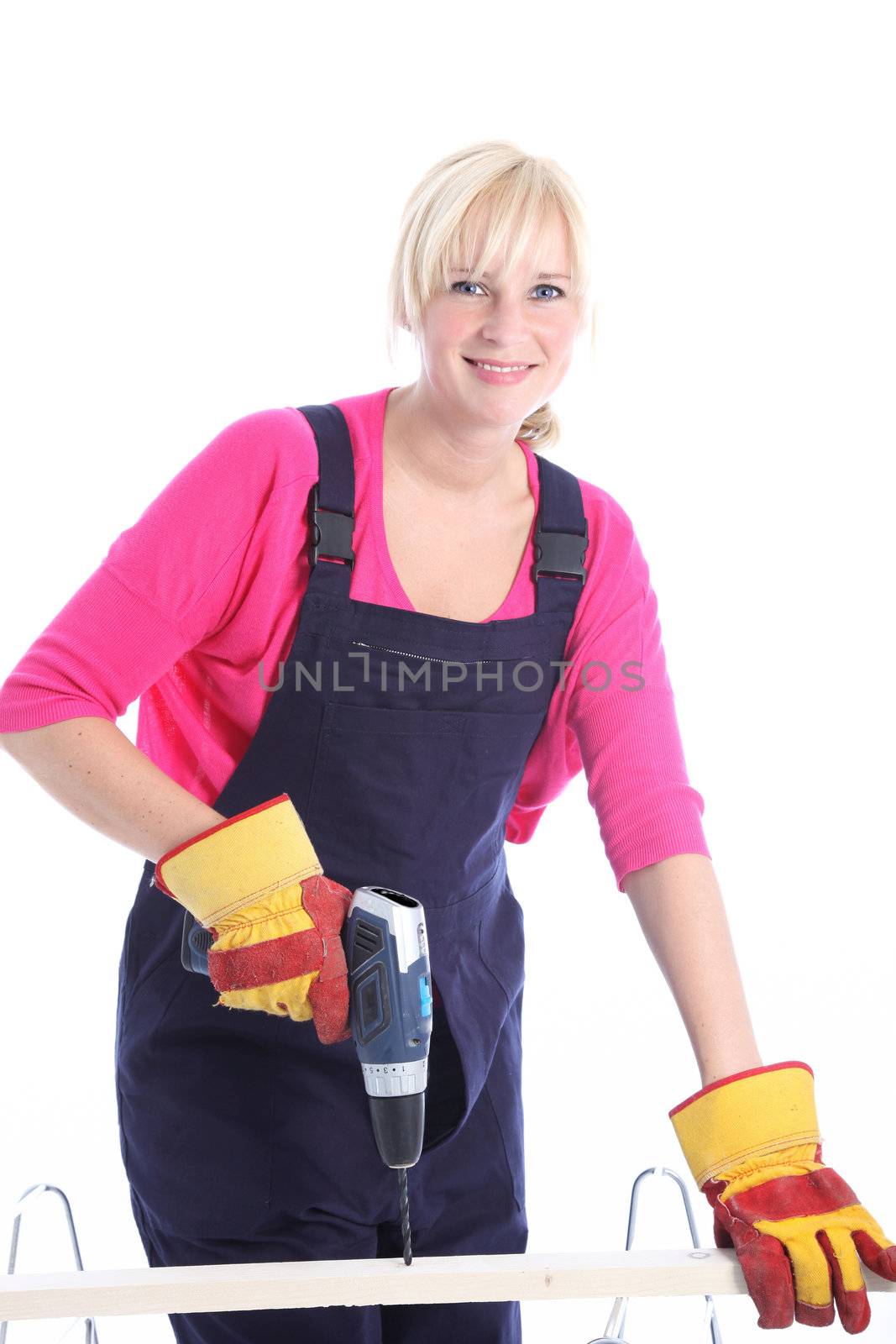 Woman carpenter in dungaress and safety gloves using a power drill to drill a hole in a length of timder isolated on white 