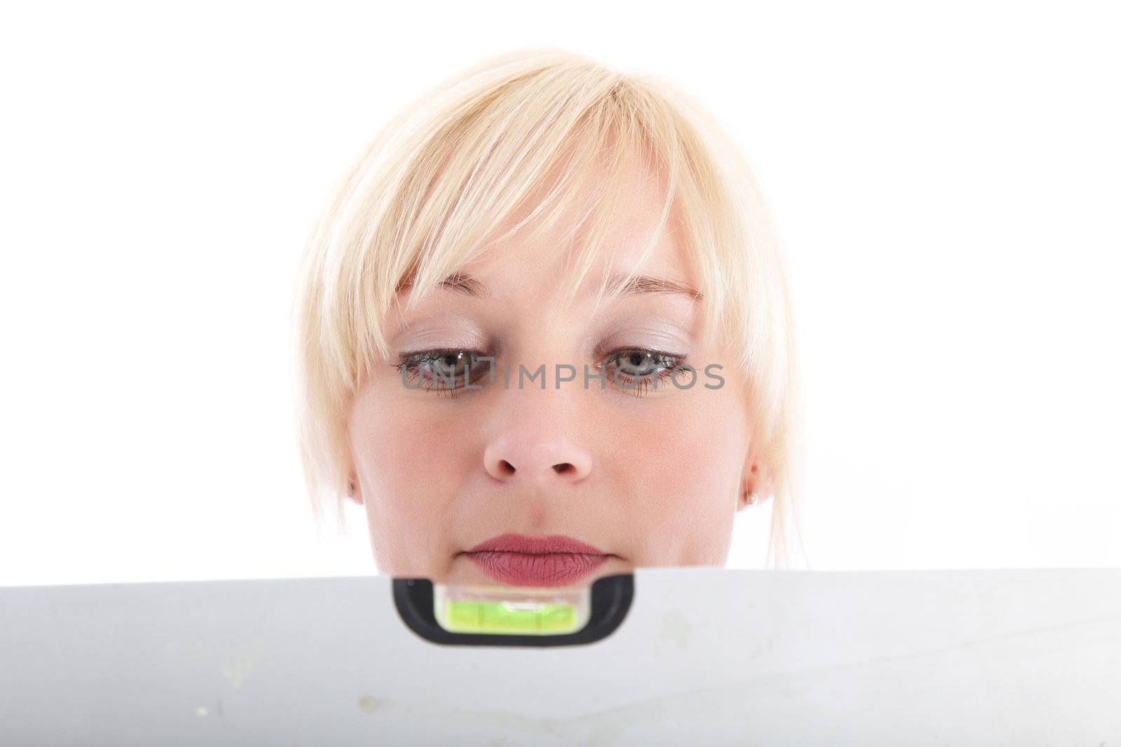 Attractive blonde woman looking at spirit level isolated on white Attractive blonde woman looking at spirit level isolated on white
