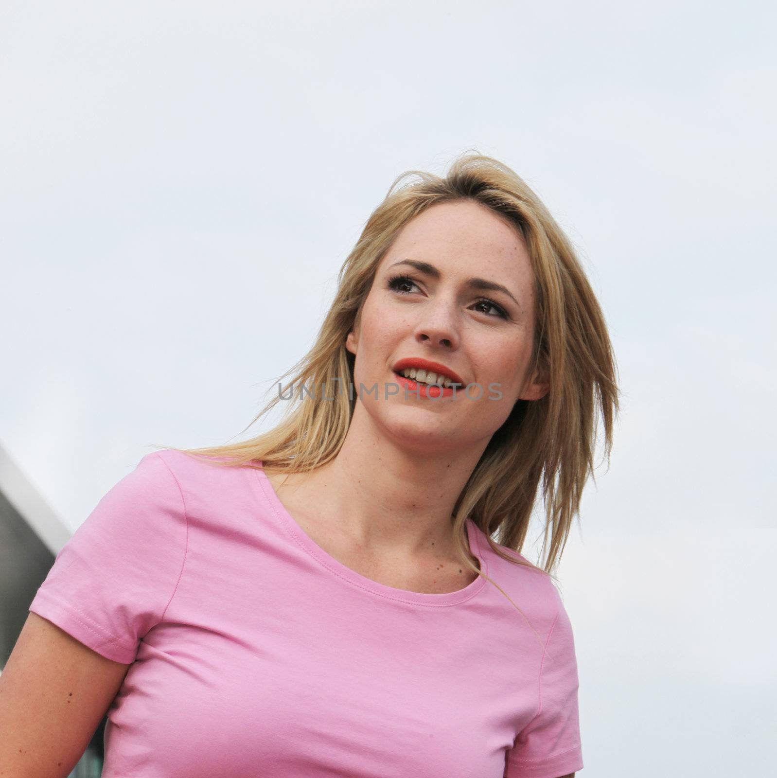 Low angle shot against blue sky of a beautiful woman looking off into the distance as though expecting someone to arrive at any moment Low angle shot of a beautiful woman looking off into the distance as though expecting someone to arrive at any moment