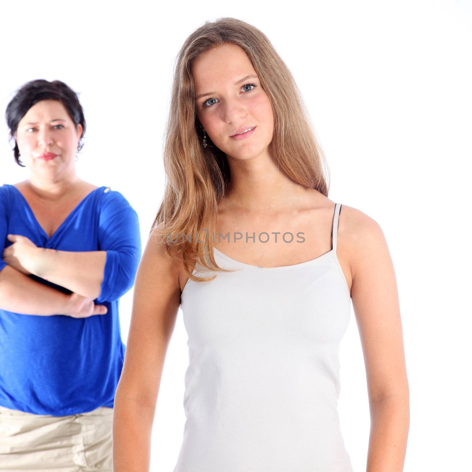 Mother standing watching her daughter with a grim expression and folded arms following a disagreement Mother standing watching her daughter with a grim expression and folded arms following a disagreement