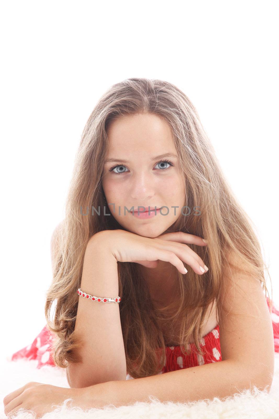 Dispirited teenage girl lying on a fluffy white carpet resting her chin on her hand with a withdrawn sad expression Dispirited teenage girl lying on a fluffy white carpet resting her chin on her hand woth a withdrawn sad expression 
