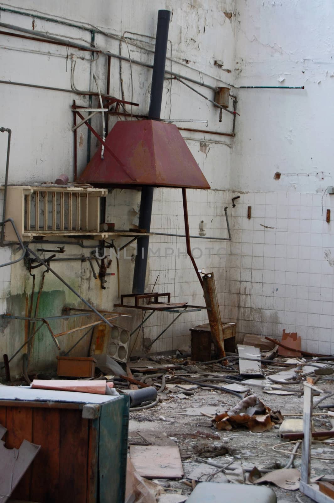 Discarded equipment and debris in abandoned factory decayed industrial interior.
