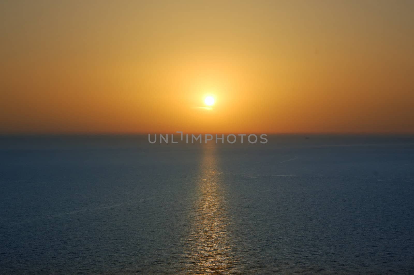 Sunset over water. Deep blue sea and orange colored sky background.