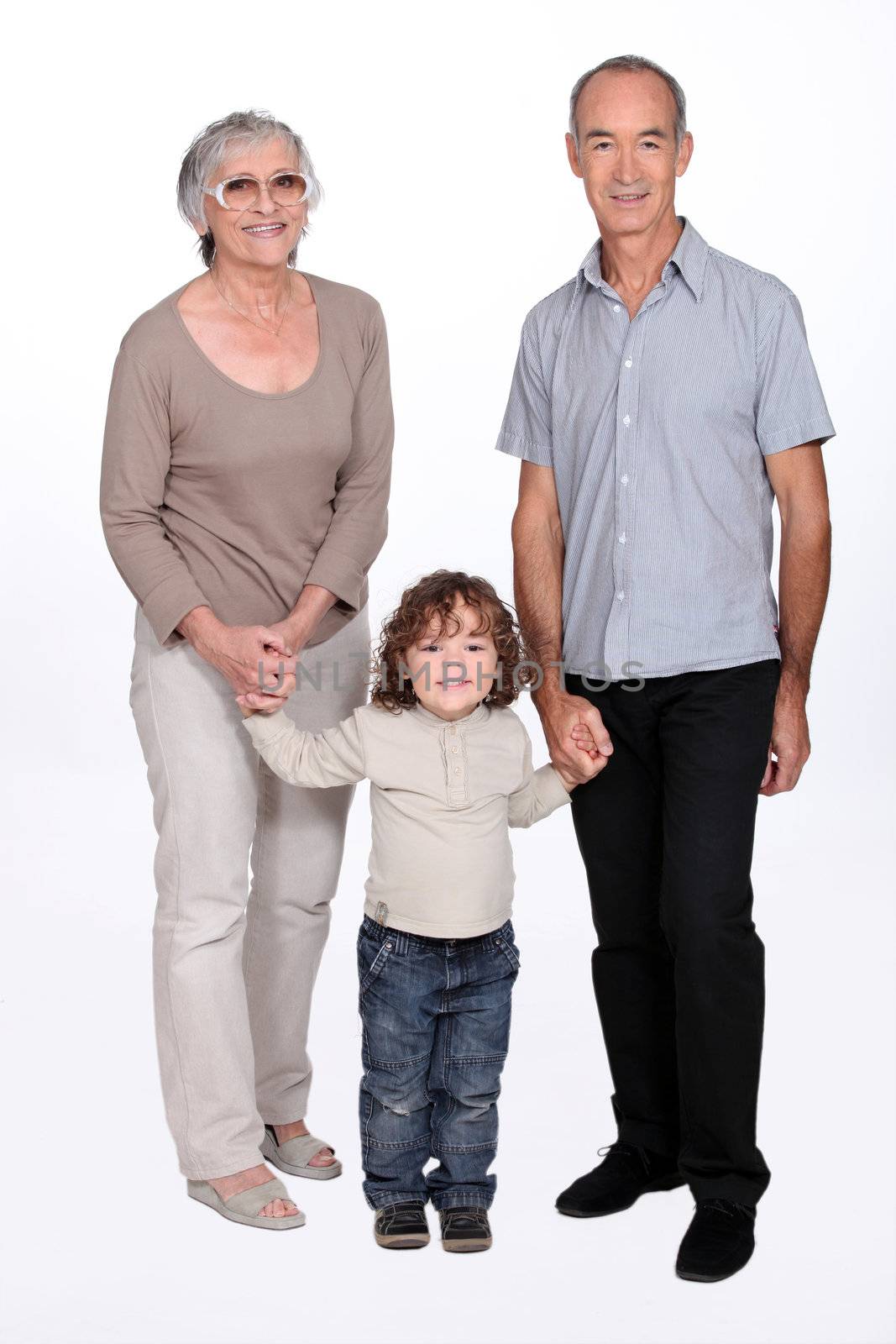 Grandparents going for a walk with their granddaughter by phovoir