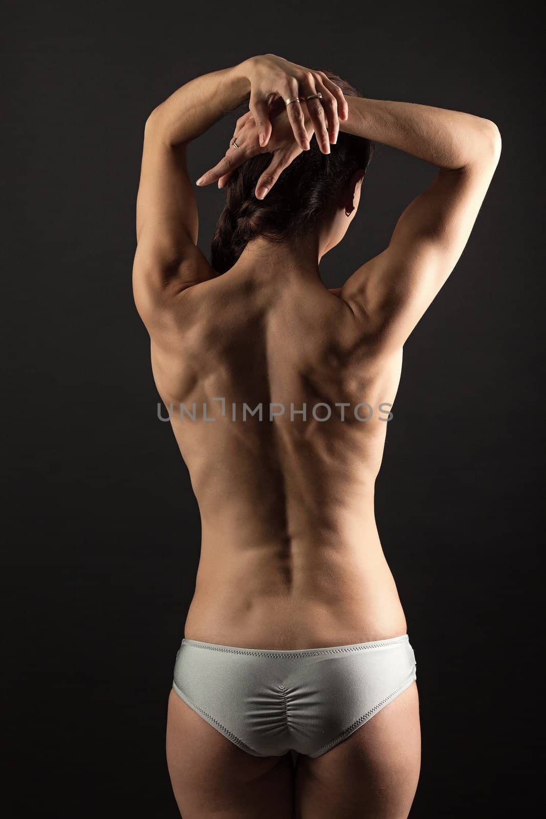 Rear view of young fitness woman over black by photobac