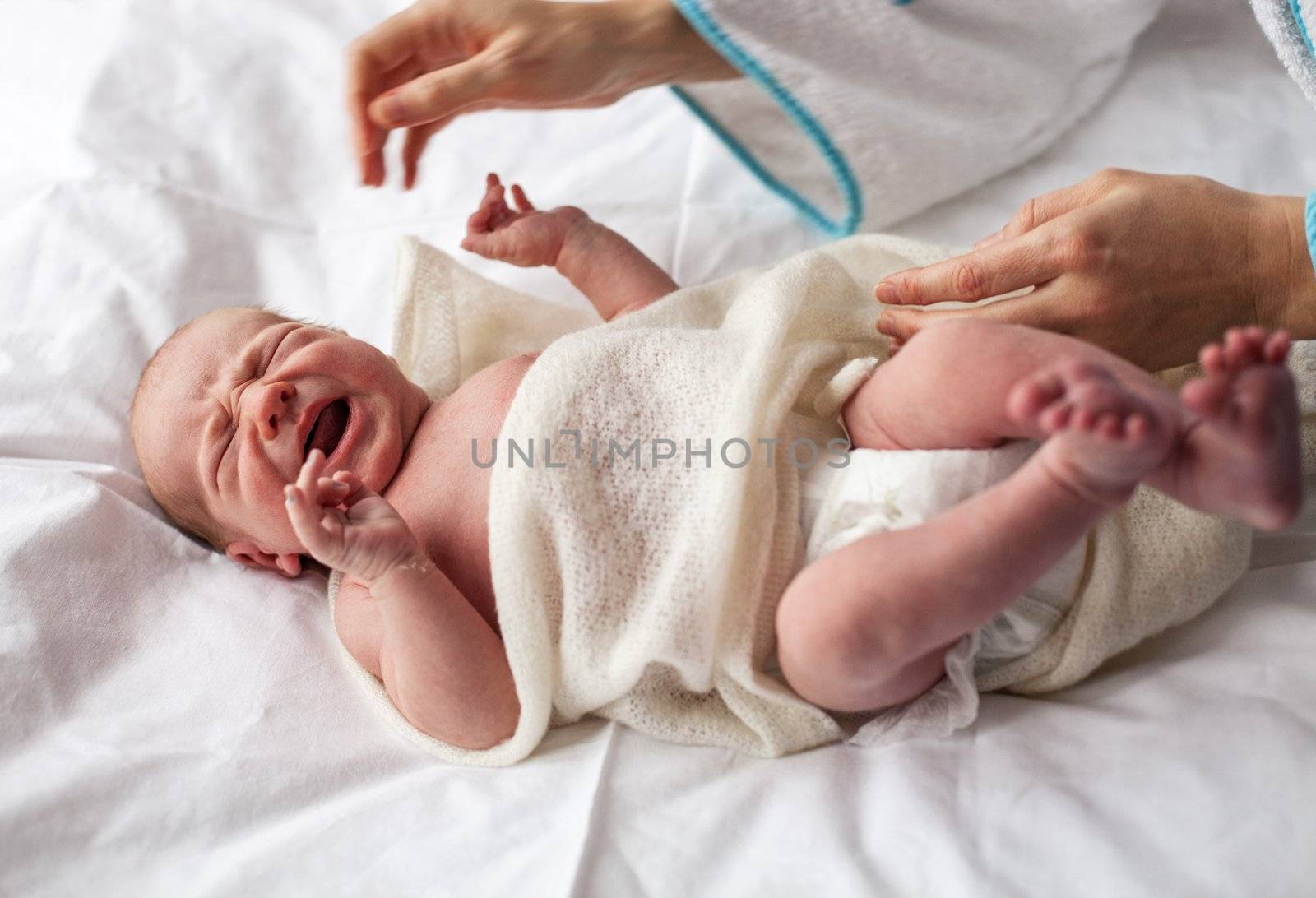 Newborn baby crying lying down on bed