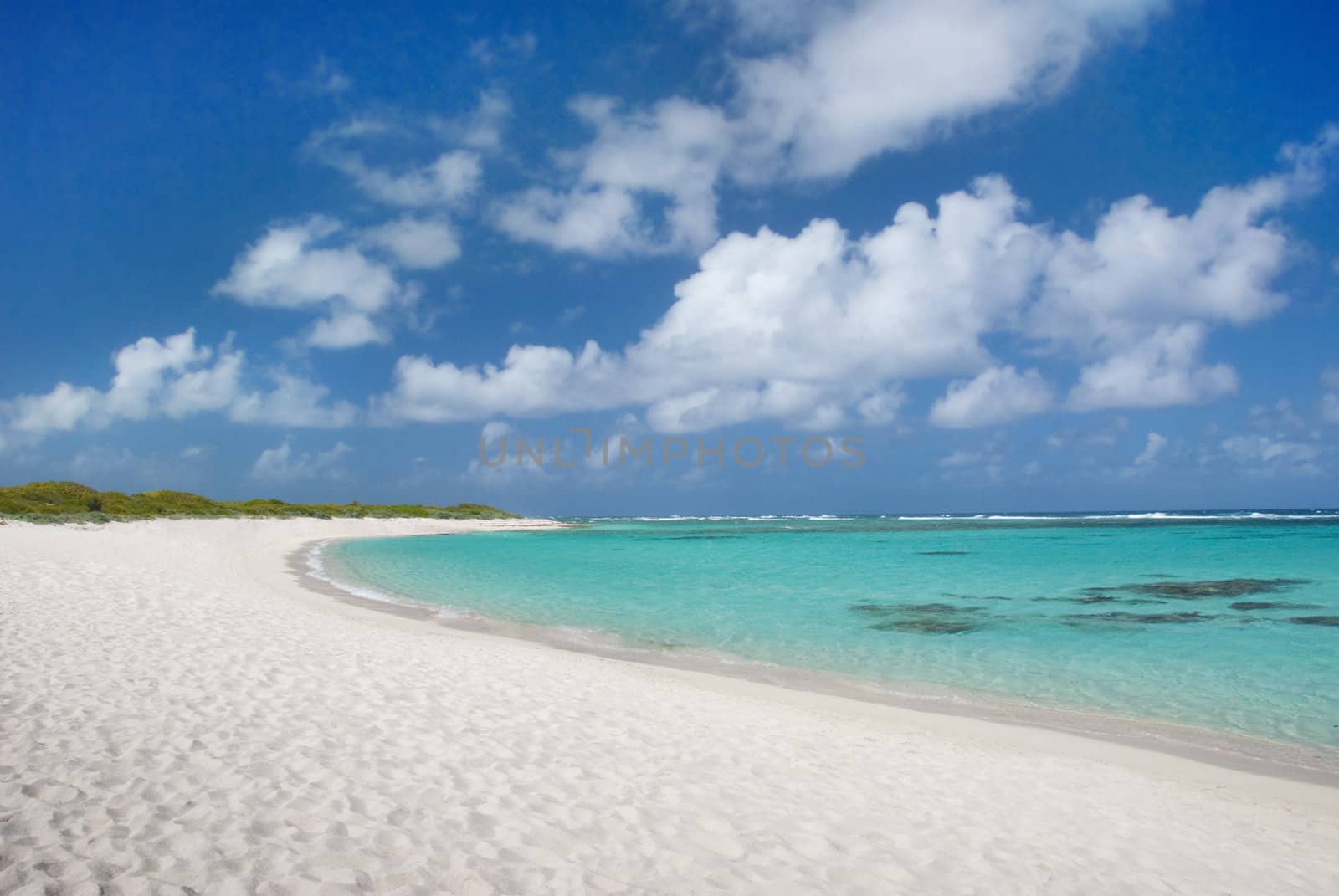 Sandy Caribbean beach with aqua water and blue cloudy sky