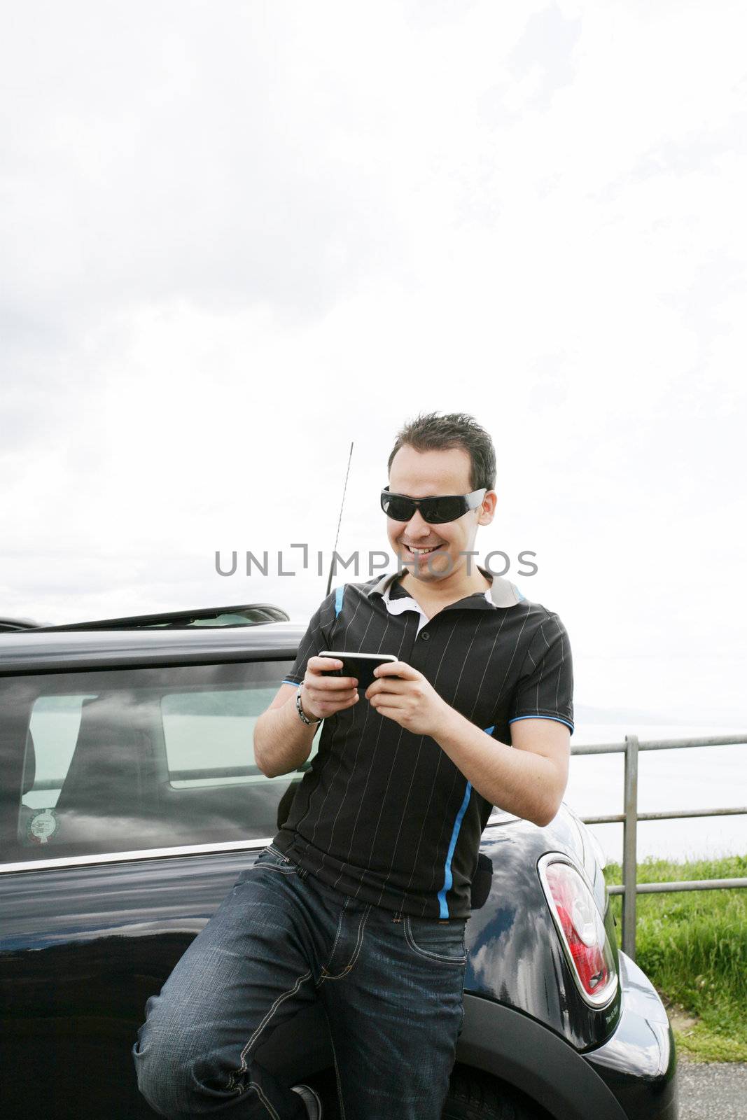 Happy man using his mobile outside his car by dacasdo