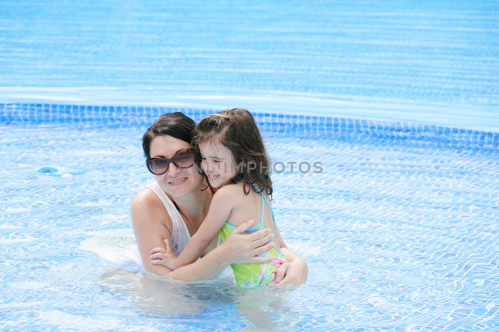 Mother and her baby having fun in the swimming pool. by dacasdo