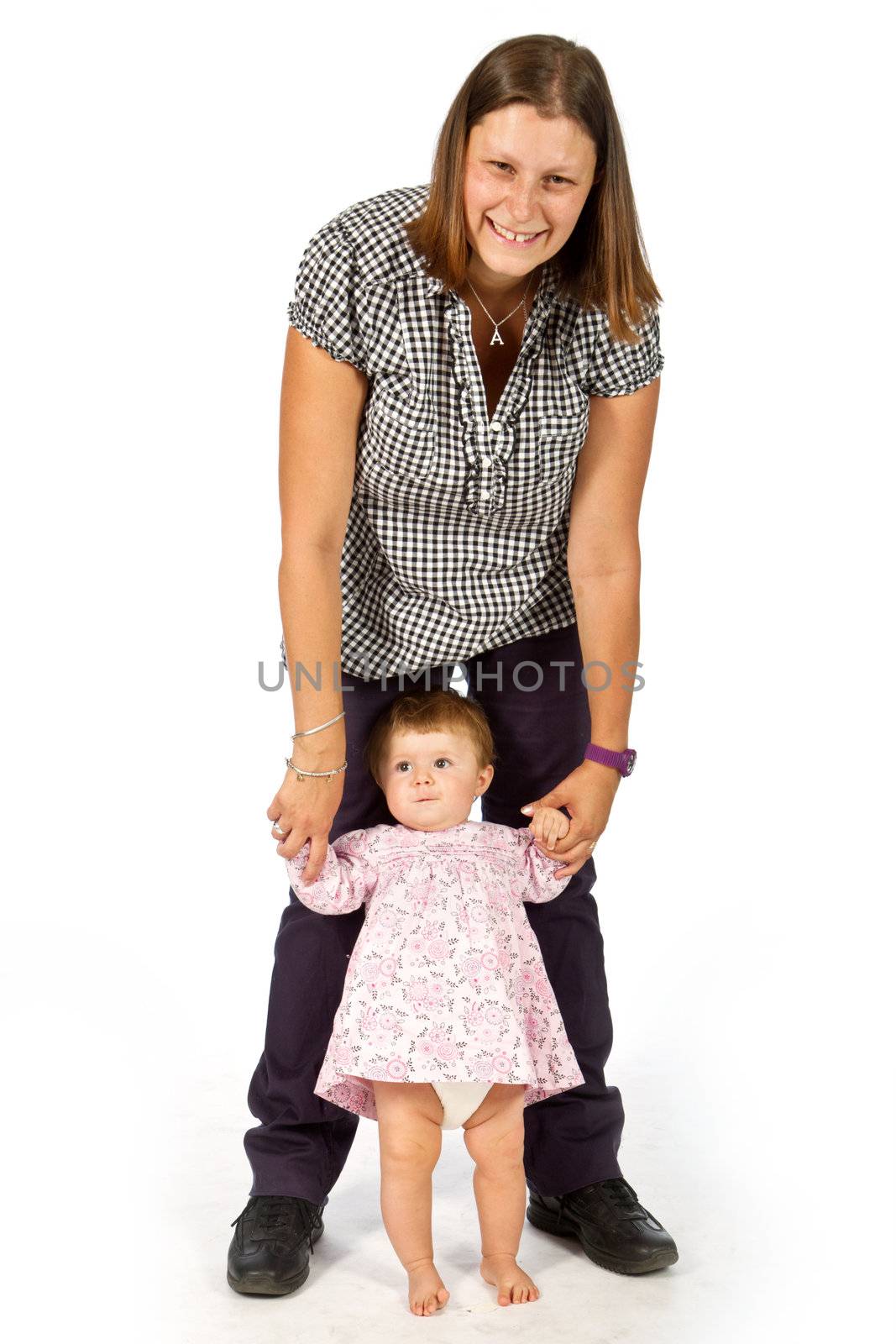 baby taking first steps with mother help on white background 