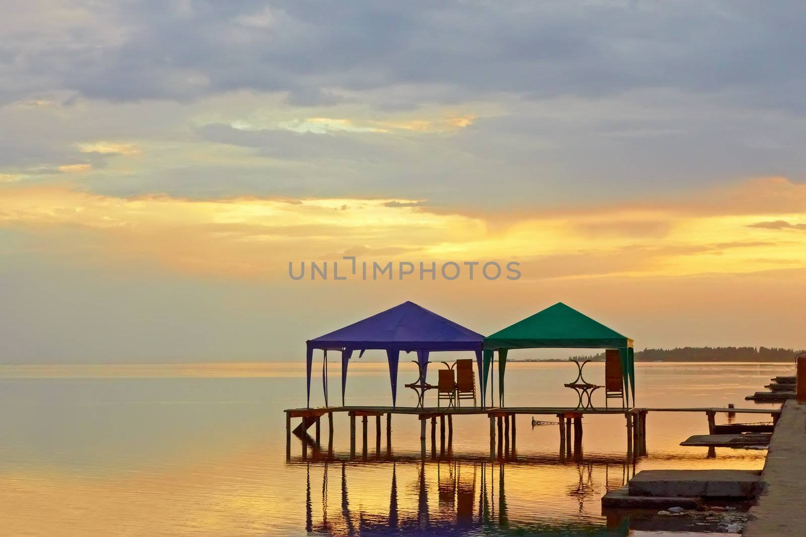 Two tents on the platform over the water near the sea coast during sunset. Skadovsk, Ukraine