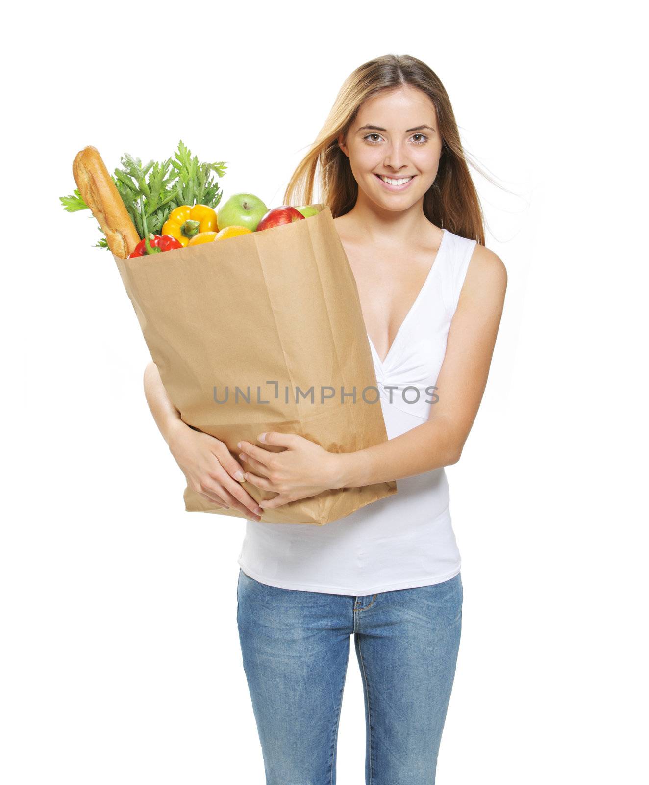 Portrait of smiling young woman holding a shopping bag full of groceries on white background