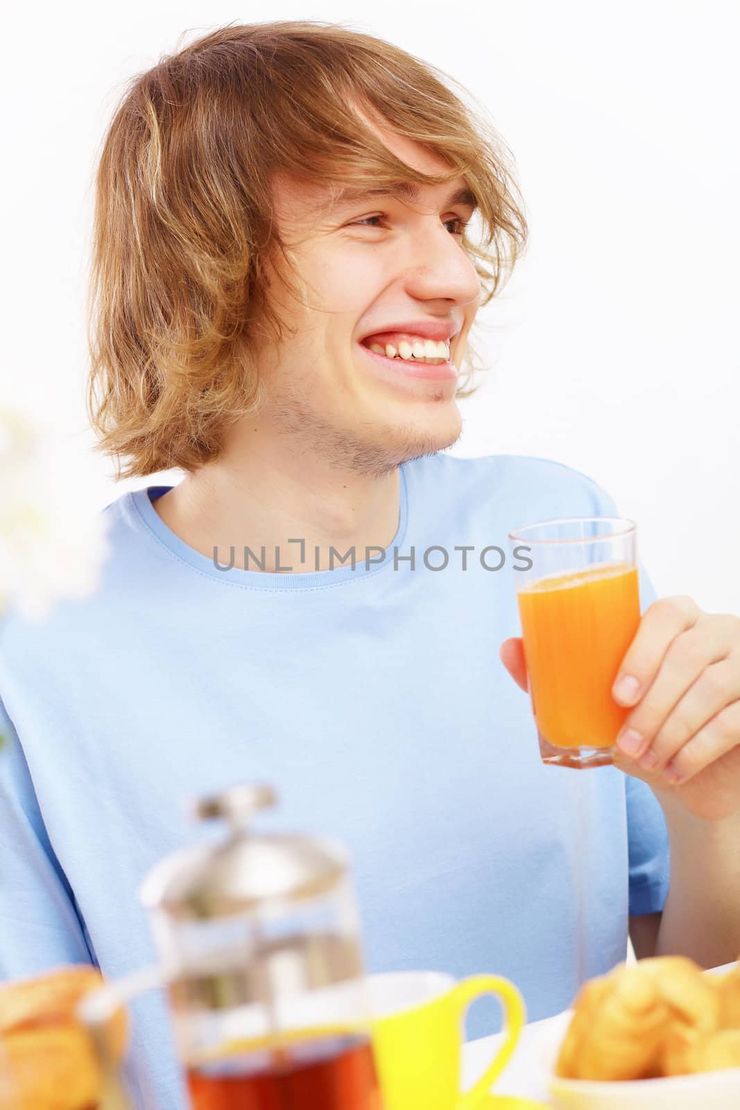 Young happy man smiling and drinking juice