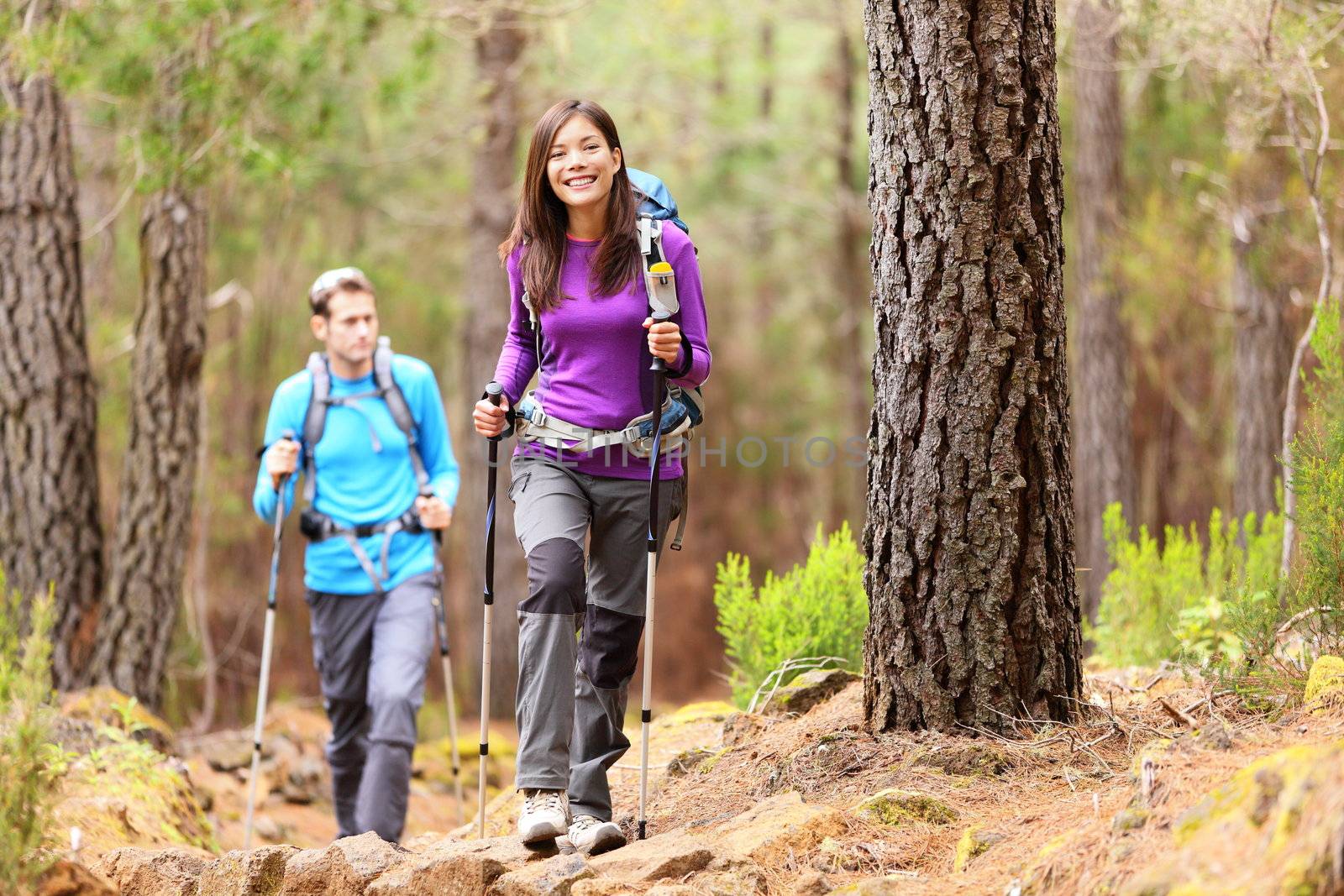 Hikers in forest. Couple hiking in fall forest. Asian woman hiker in front smiling happy. Photo from Aguamansa, Orotava, Tenerife, Canary Islands, Spain.