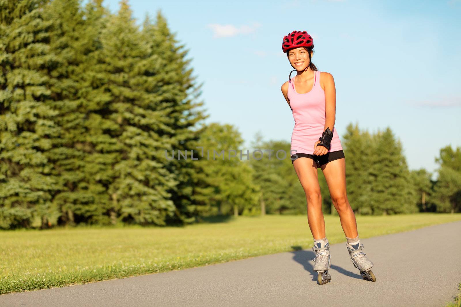 Roller skating girl in park rollerblading on inline skates. Mixed race Asian Chinese / Caucasian woman in outdoor activities.