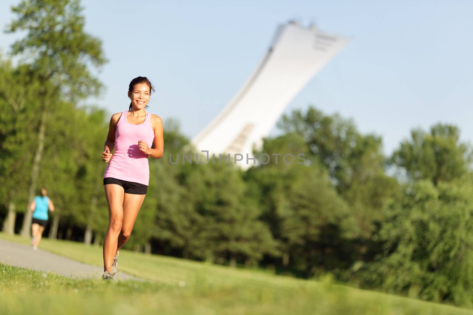 Running fitness in summer city park in Montreal, Quebec. Sport fitness woman running in park on summer day. Asian female runner during outdoor workout. Fit sport fitness model of mixed Asian / Caucasian ethnicity.