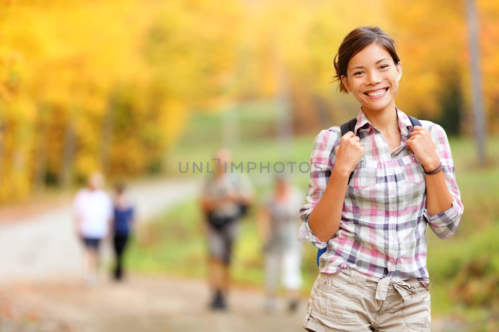 Autumn hiking girl. Female hiker looking around in forest in autumn colors. Beautiful young woman on hike.