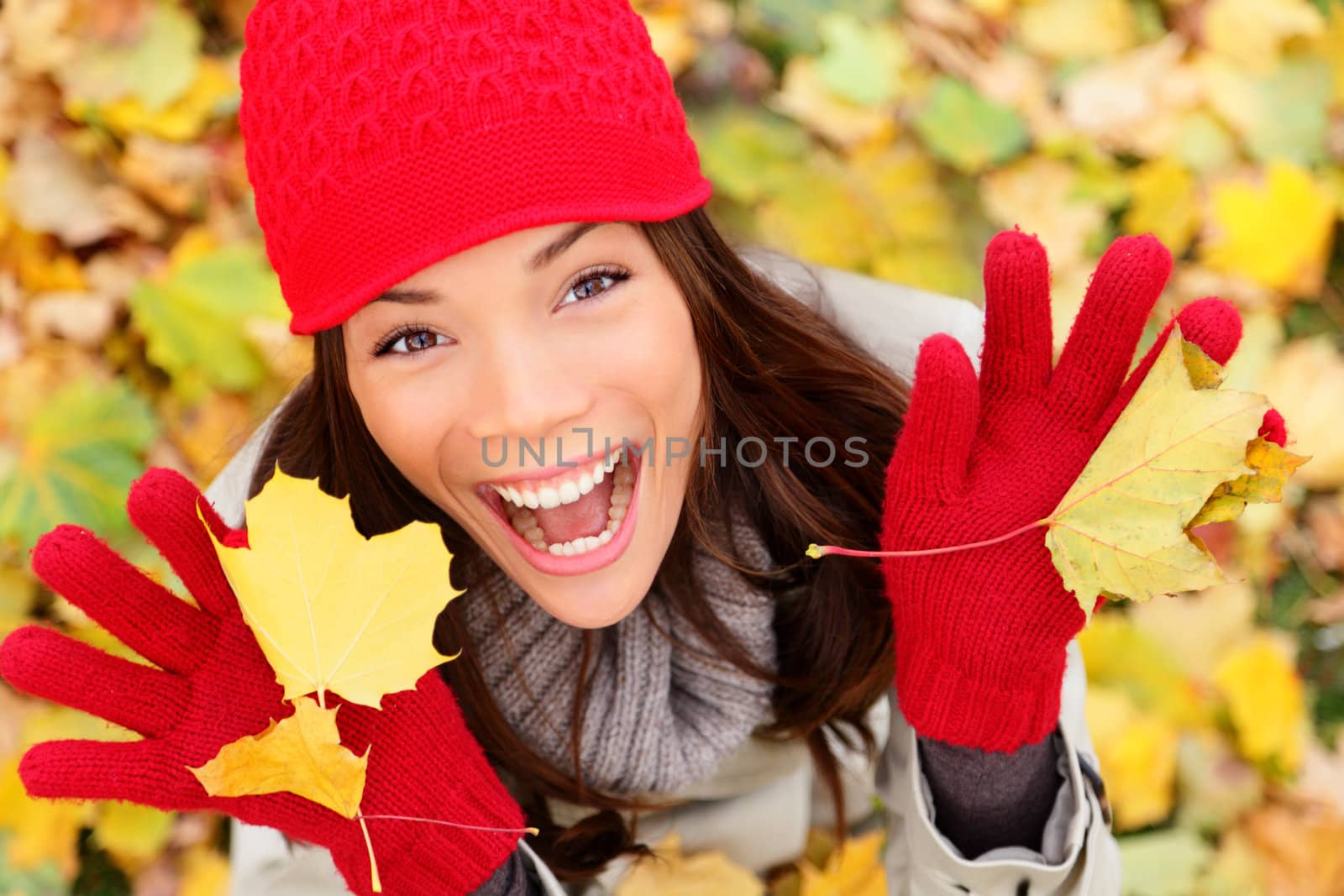 Happy autumn woman playing in leaves. utumn portrait of happy lovely and beautiful mixed race Asian Caucasian young woman in forest in fall colors.