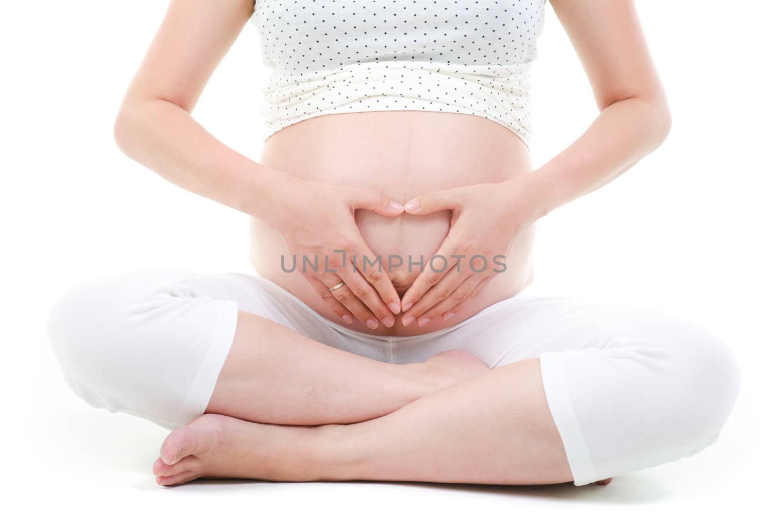 Pregnant woman forming love shape on her 8 months pregnant belly