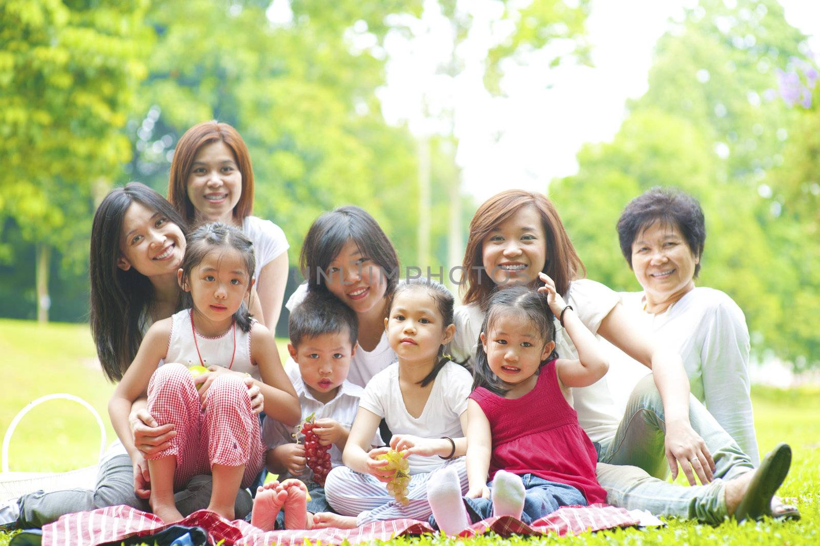 Happy Asian family enjoying picnic at outdoor park