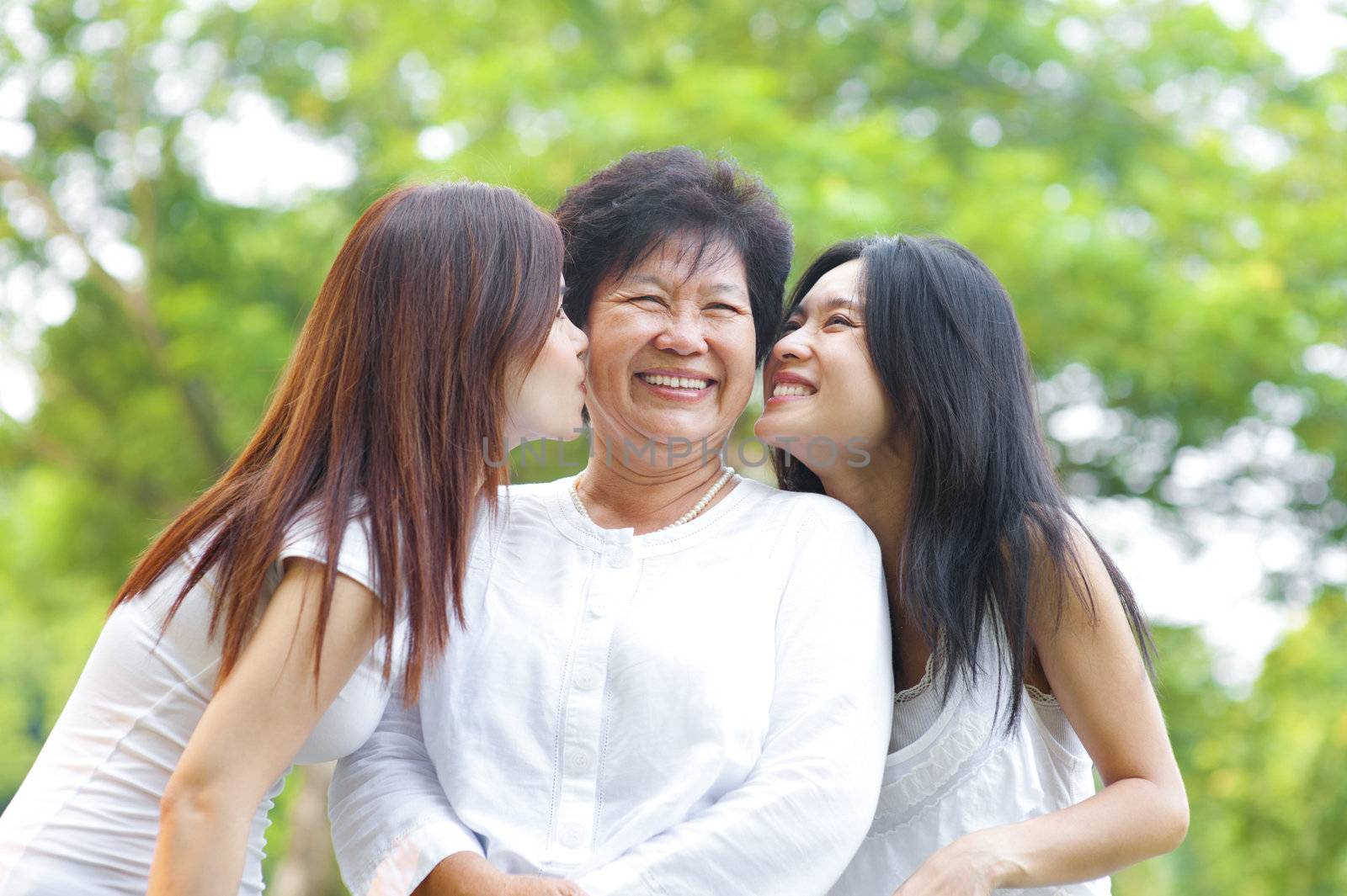 Young Asian daughter kissing their senior mother, outdoor park