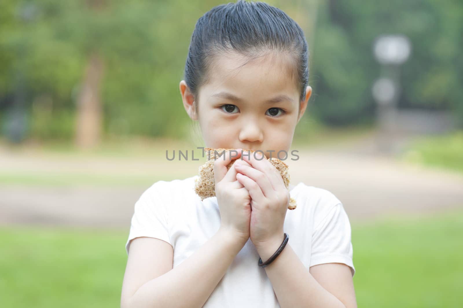 Little Asian girl eats a sandwich on fresh air