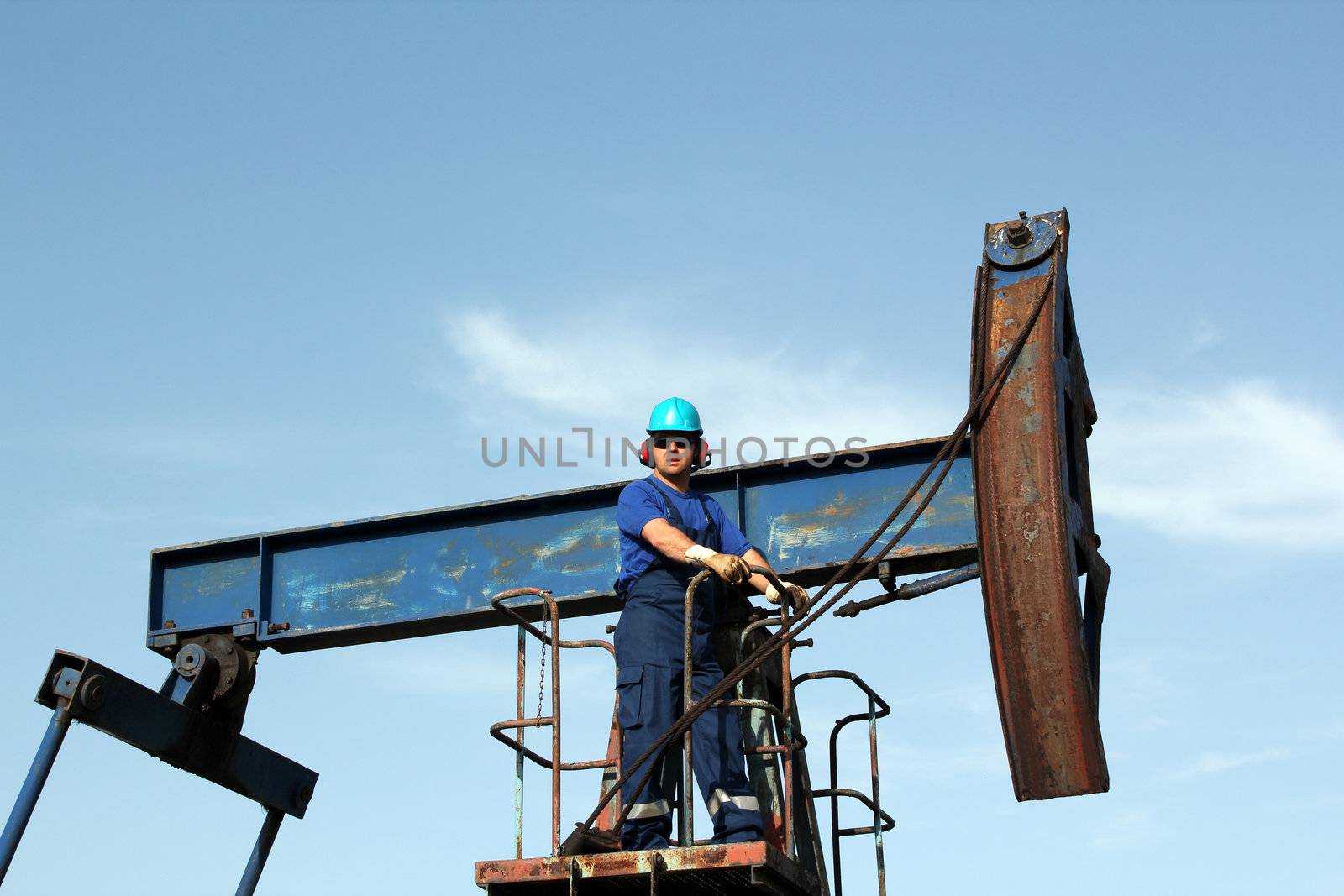 oil worker with sunglasses standing at pump jack