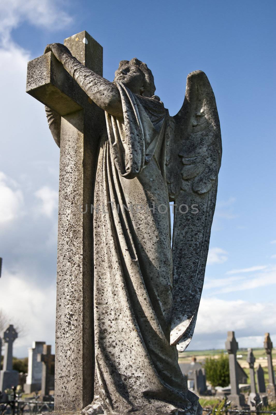 Angel statue embracing a cross and celtic graveyard in Ardmore county Waterford, Ireland with added grain