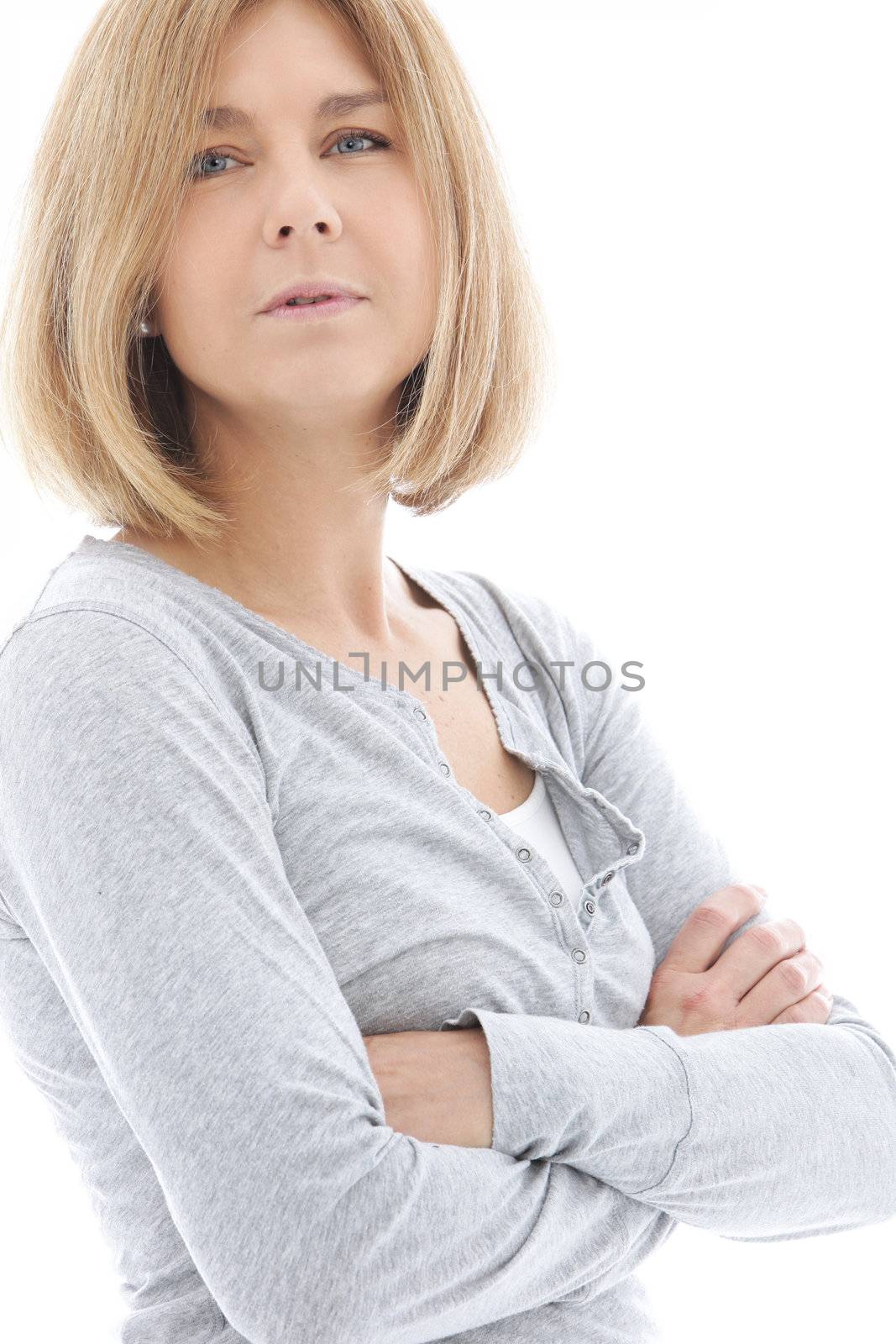 Thoughtful woman with shoulder length blond hair standing sideways with folded arms looking at the camera, isolated on white