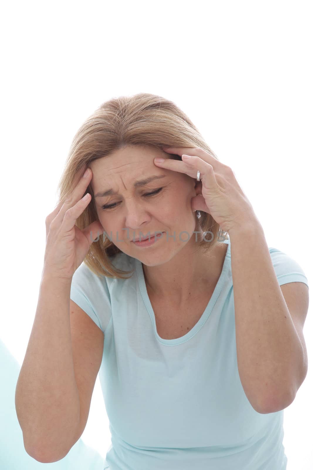 Woman suffering from a migraine or bad headache grimacing in pain and holding her fingers to her throbbing temples, isolated on white