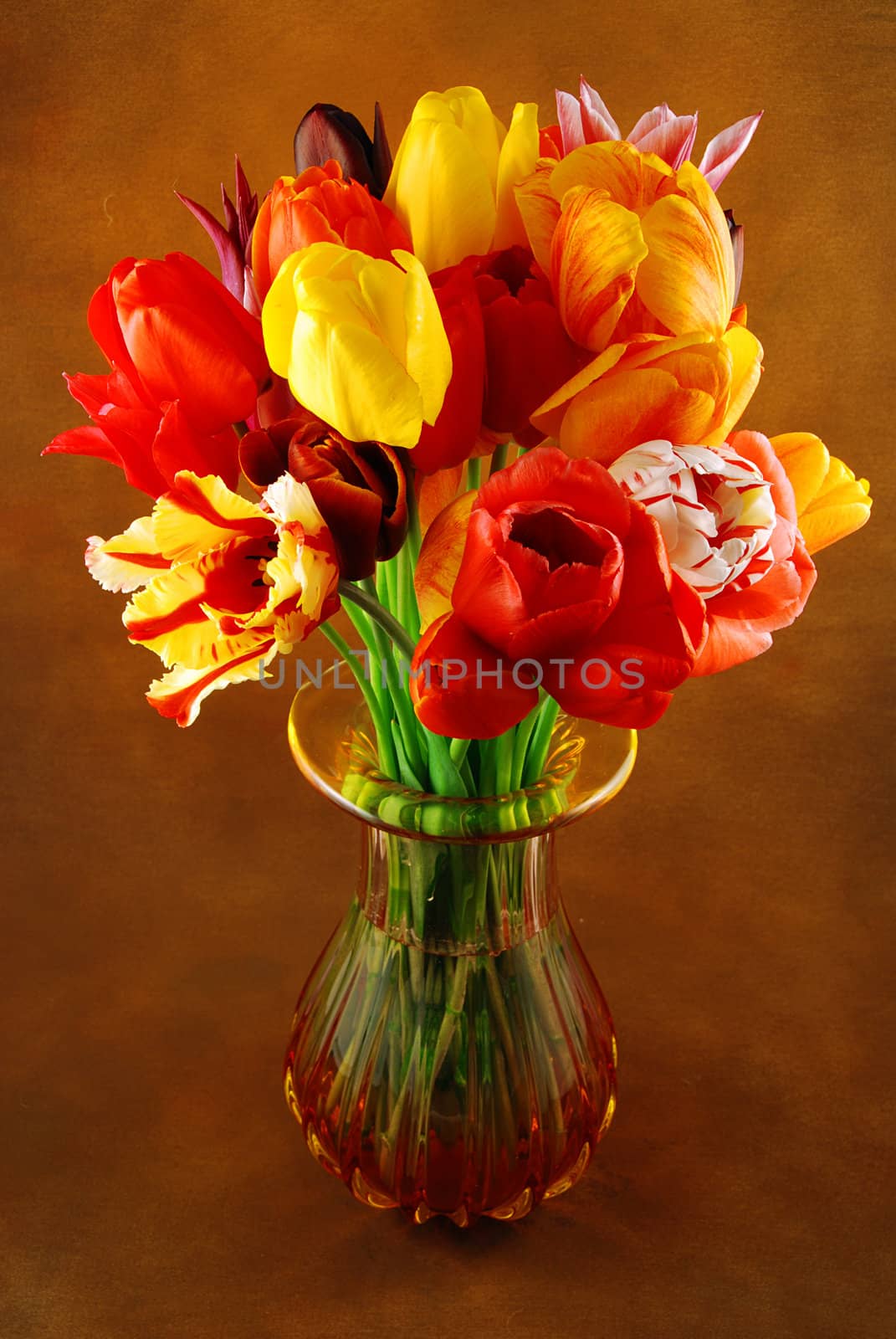 Bunch of beautiful spring flowers - colorful tulips in a vase against brown background