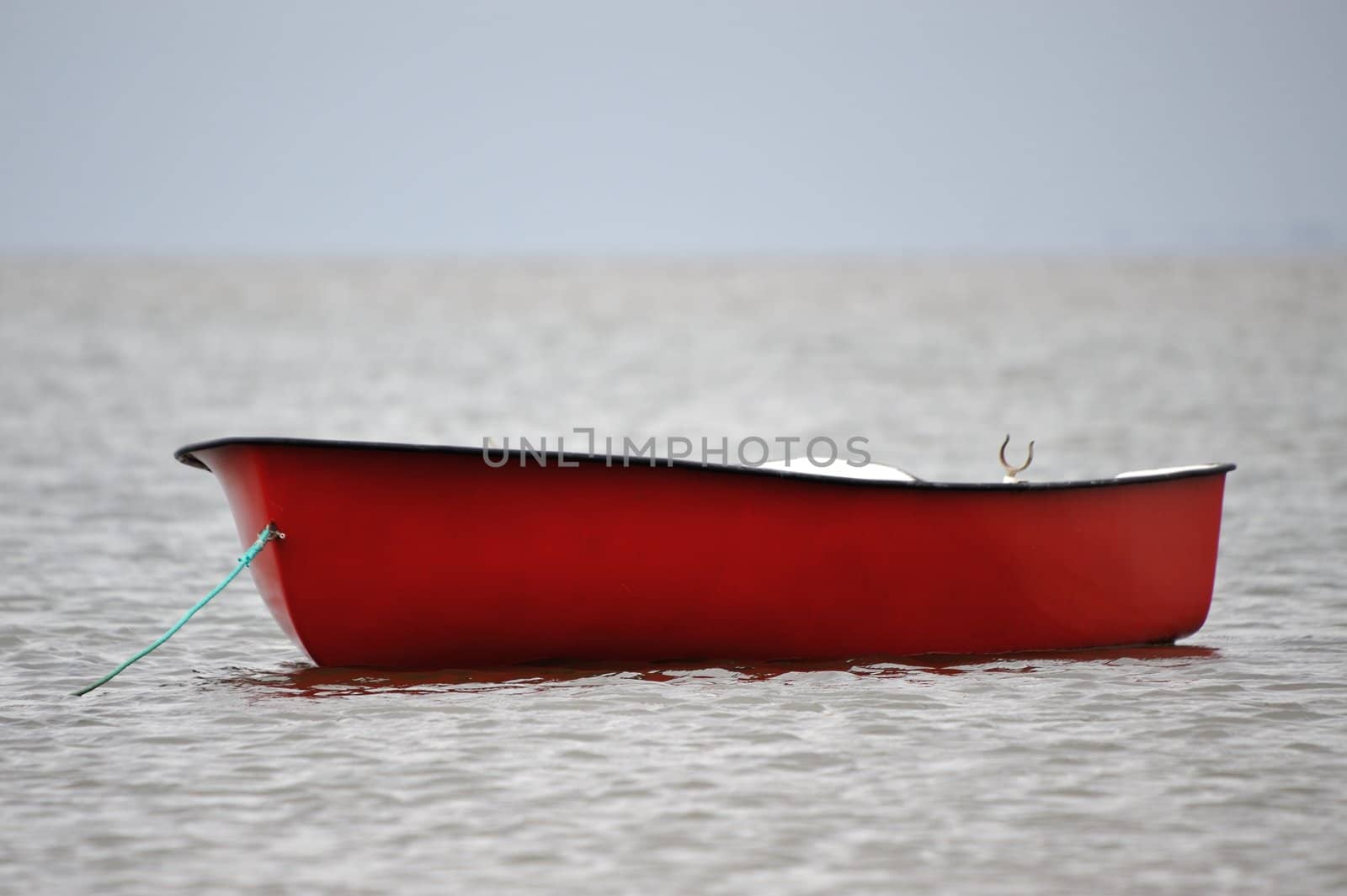 A lonely red boat on the sea.