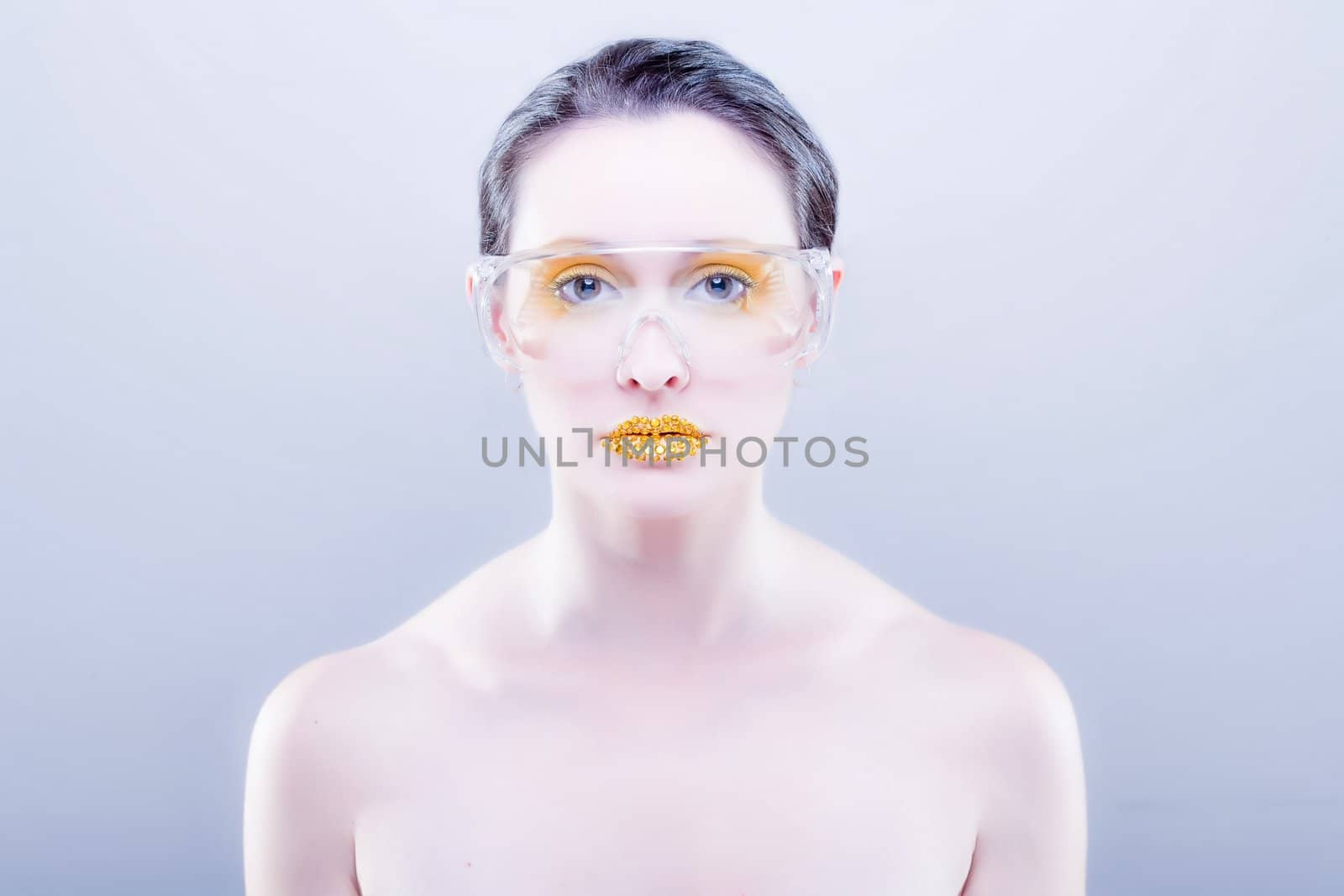 Young caucasian woman with gold fashion makeup wearing clear glasses and gold diamonties on her lips