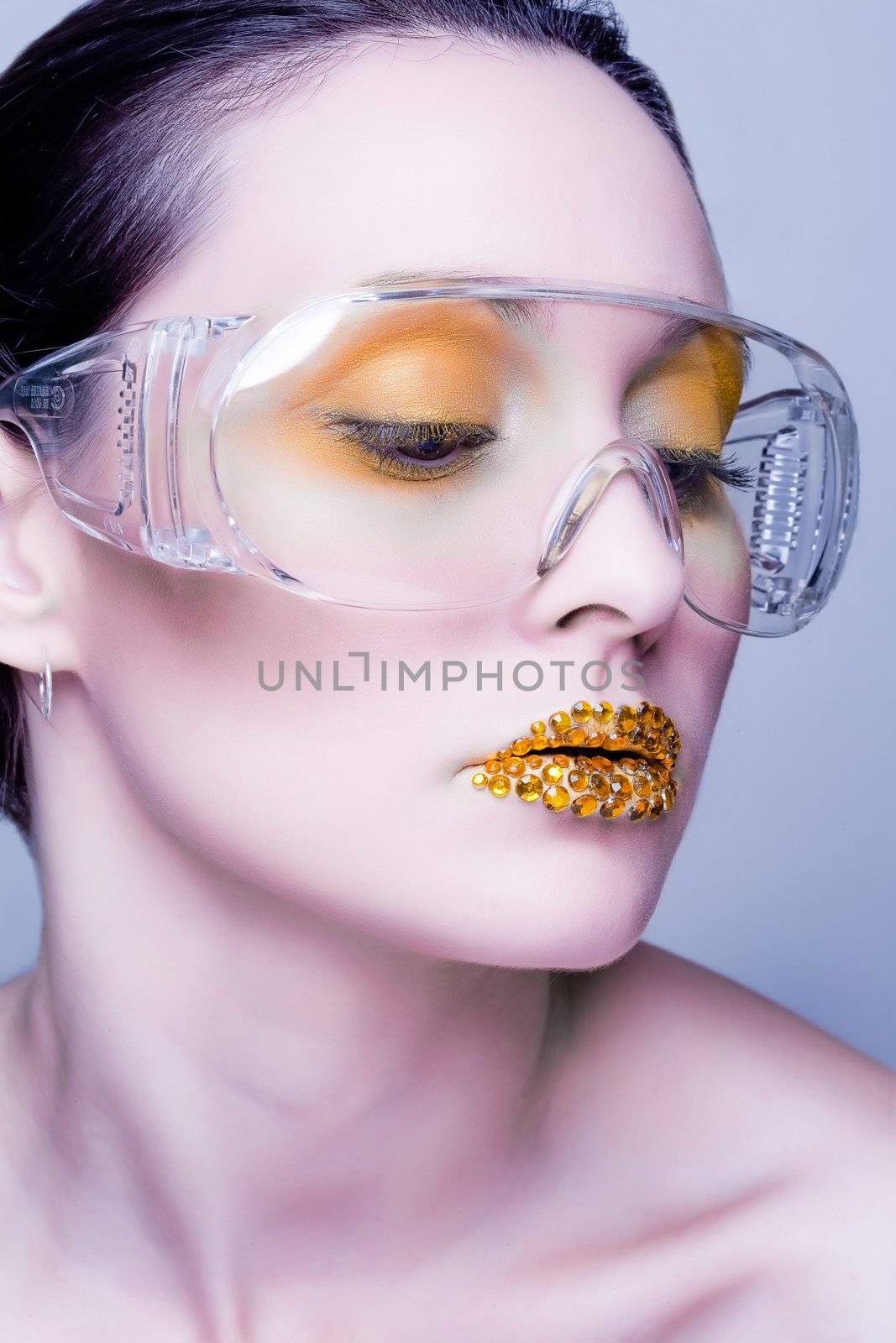 Young caucasian woman with gold fashion makeup wearing clear glasses and gold diamonties on her lips