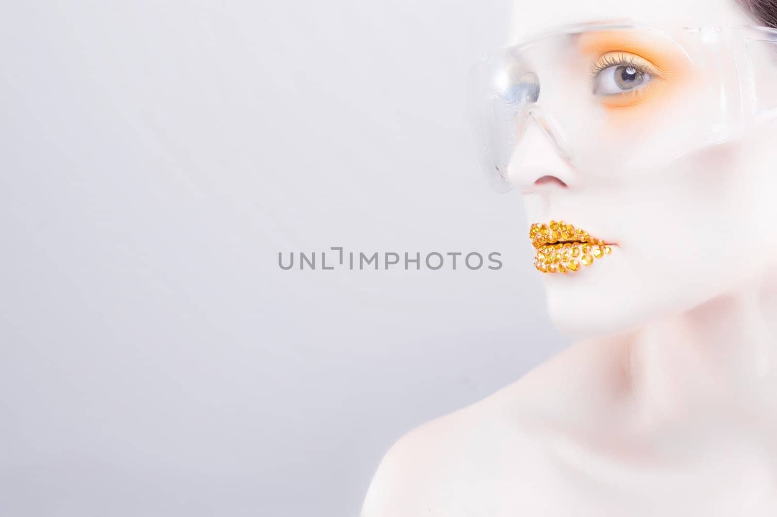 Young caucasian woman with gold fashion makeup wearing clear glasses and gold diamonties on her lips