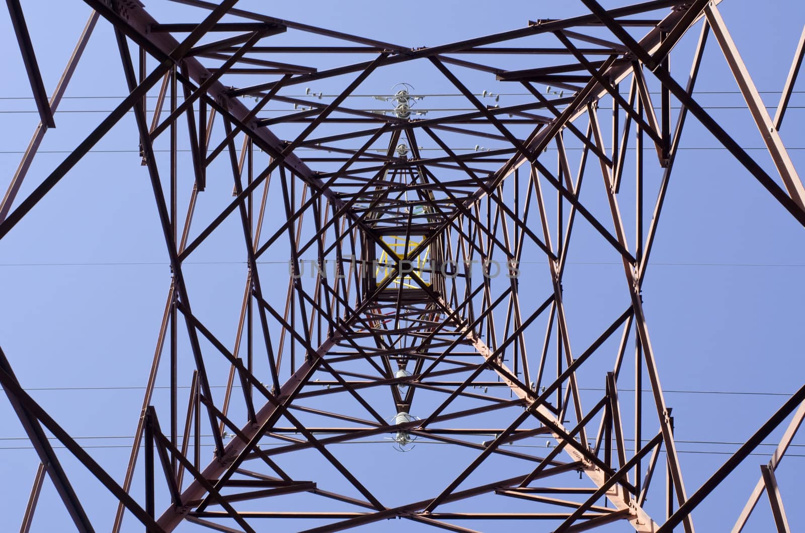 Transmission tower as seen from below towards a blue sky