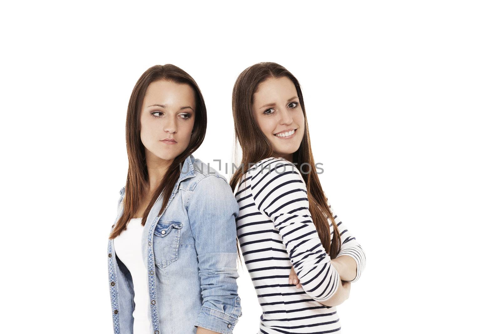 one happy and one upset teenager standig back to back on white background